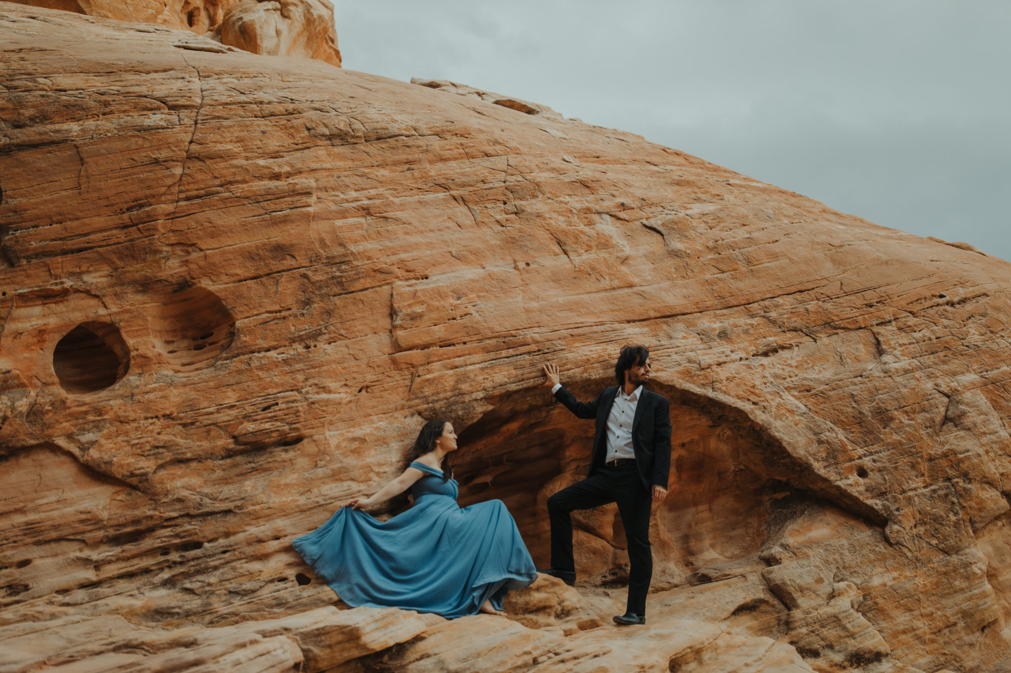 Couple posing on tan cliffside in formal clothes