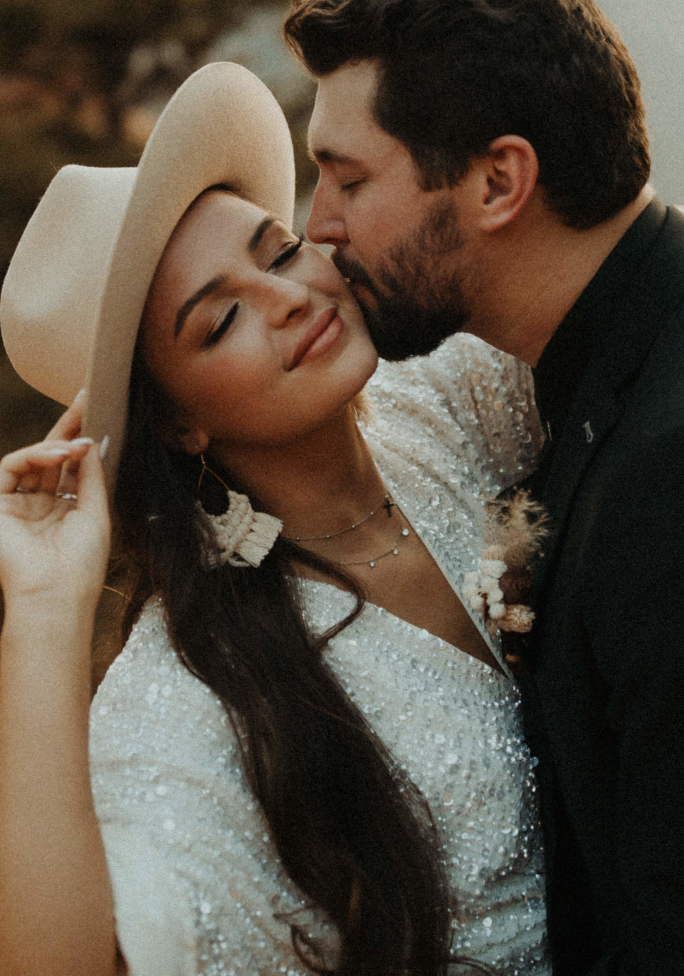 boho desert couple close up kissing with hand on hat