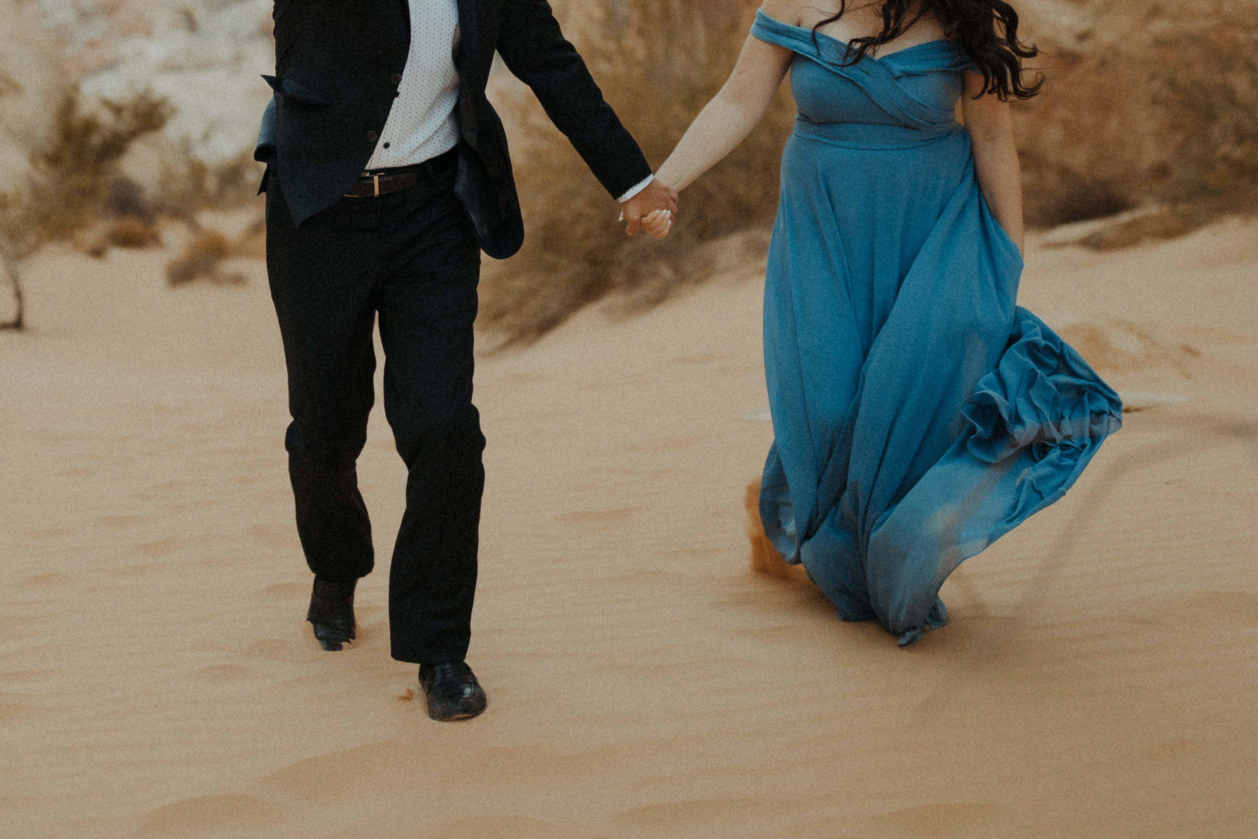 Couple Holding hands in desert while wearing formal clothes
