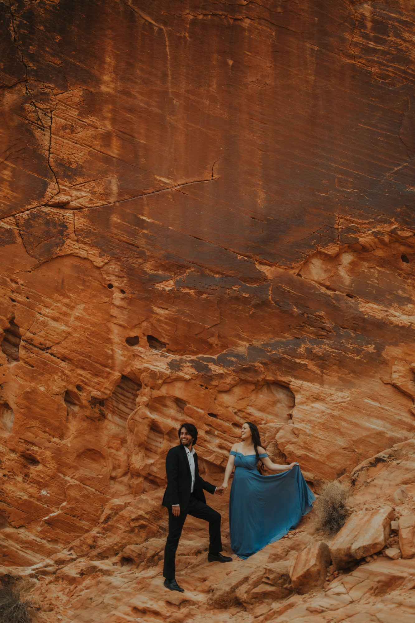 Couple wearing formal attire walking down red cliff