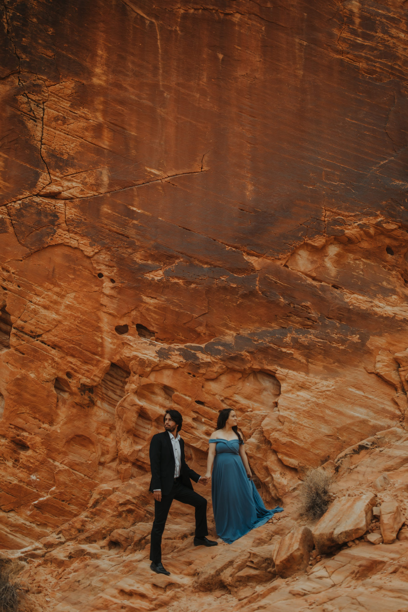Couple wearing formal attire walking down red cliff