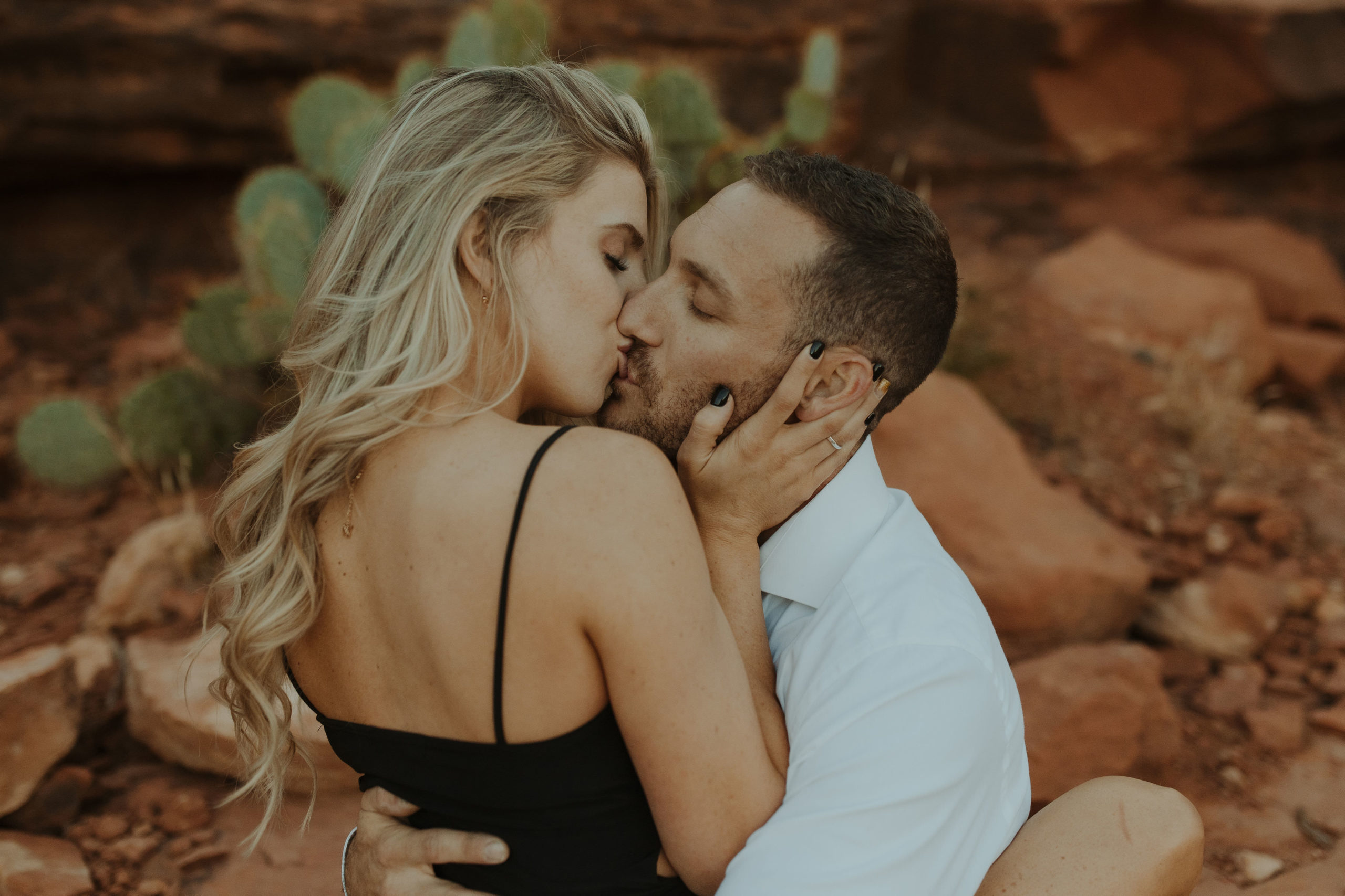 Engagement photos with couple and their dog cuddling in front of Cathedral Rock in Sedona in formal clothing