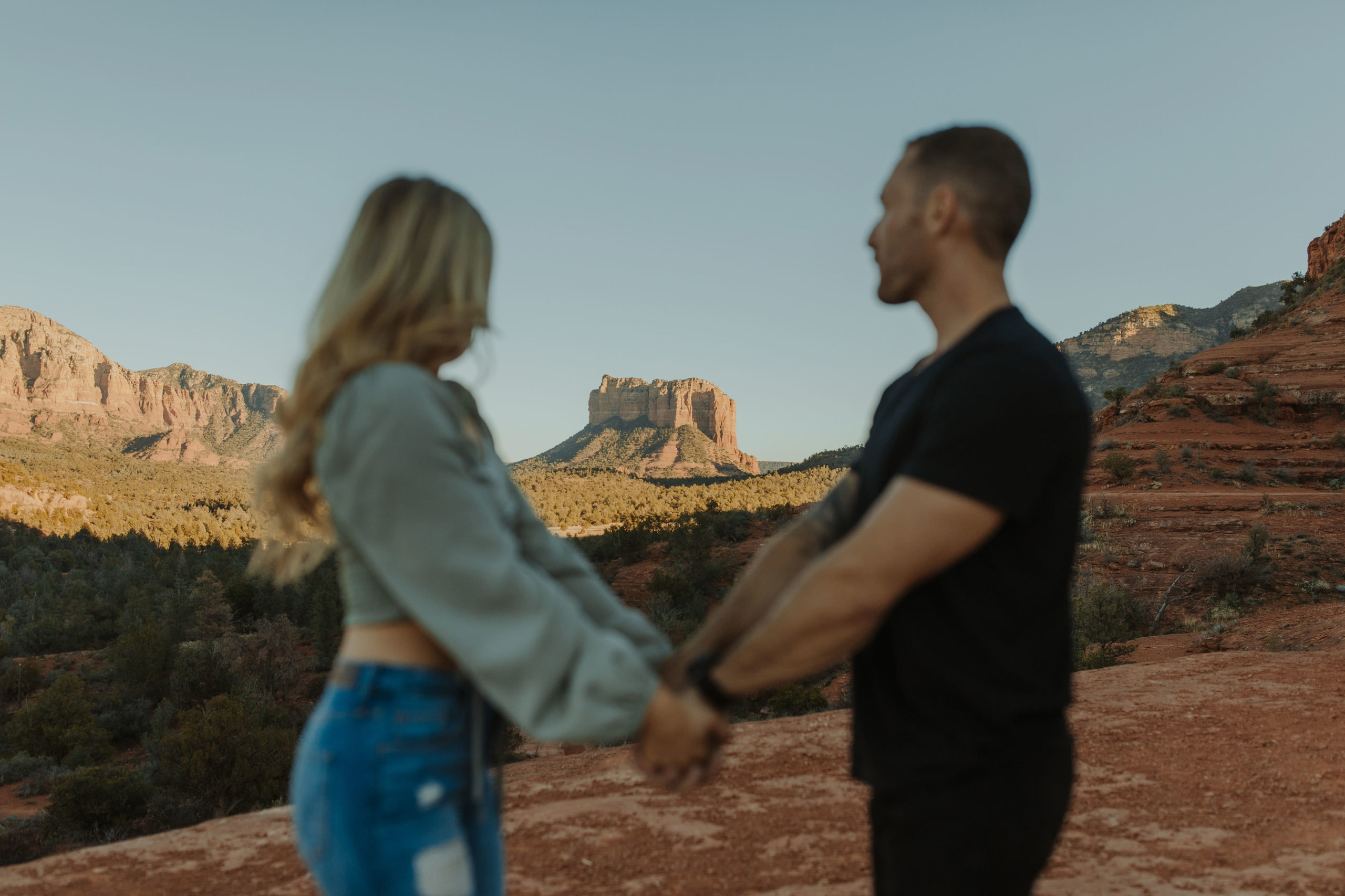 Couple standing in front of Cathedral Rock in Sedona for engagement photos in casual clothes 