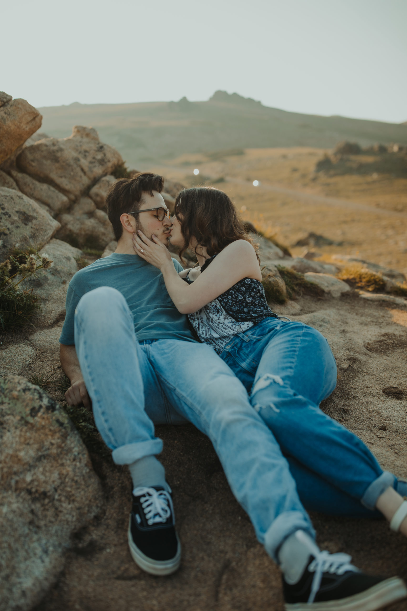 Couple all cuddled up and kissing in casual clothes in the rocky mountains