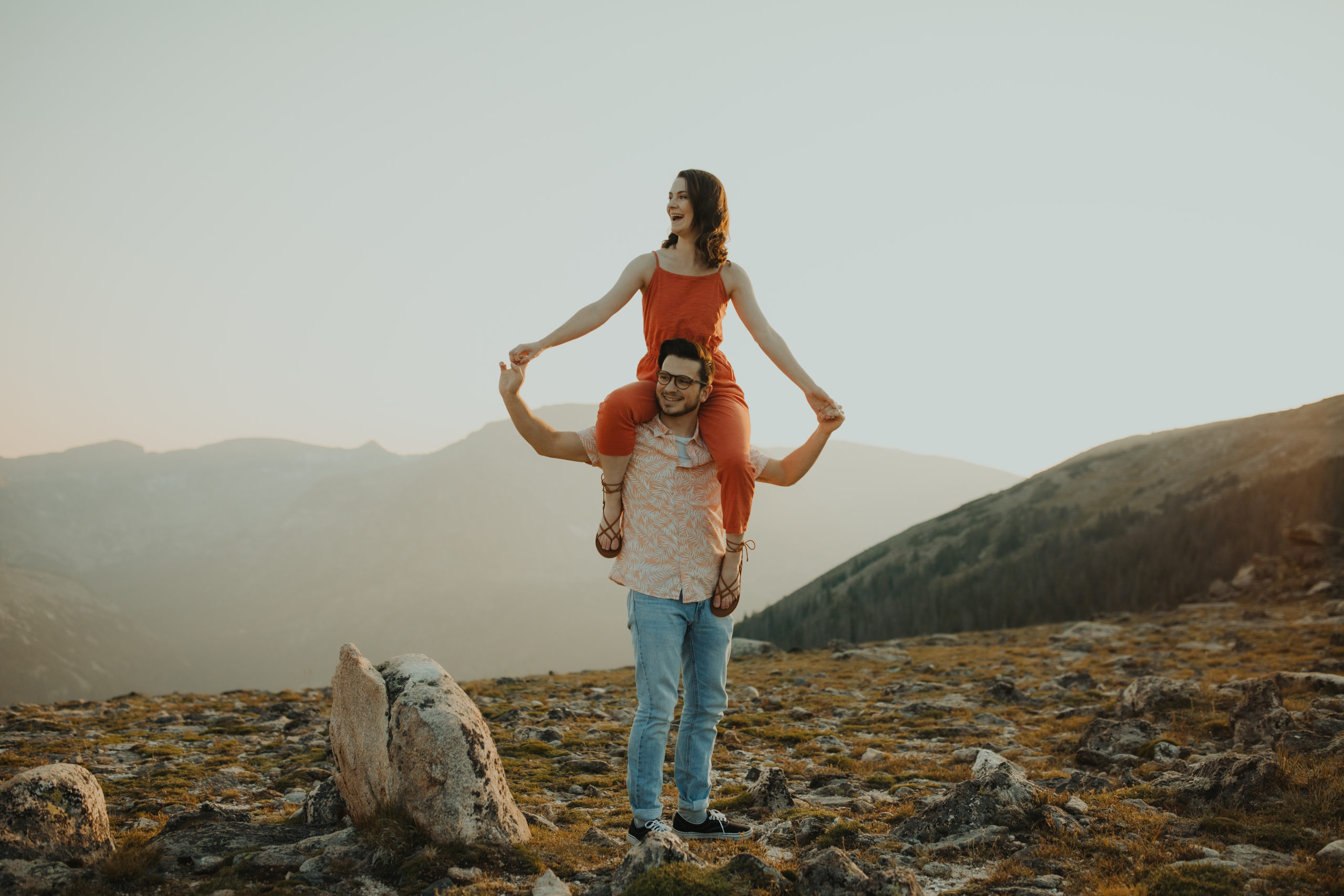 Couple holding hands while wife is on husband's shoulders in bright orange matching outfits
