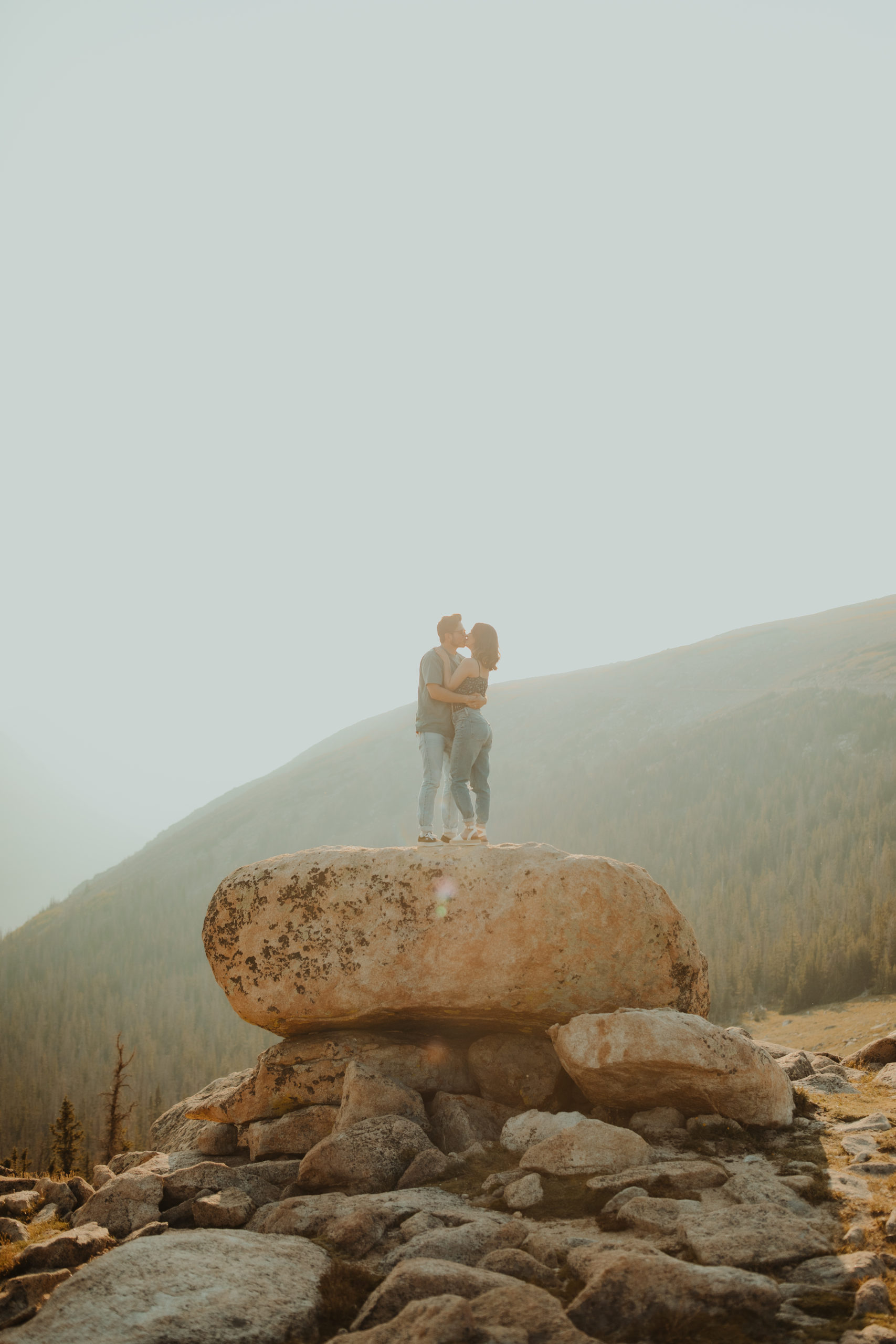 Colorado Rocky Mountain view in background of couple holding each other and kissing 