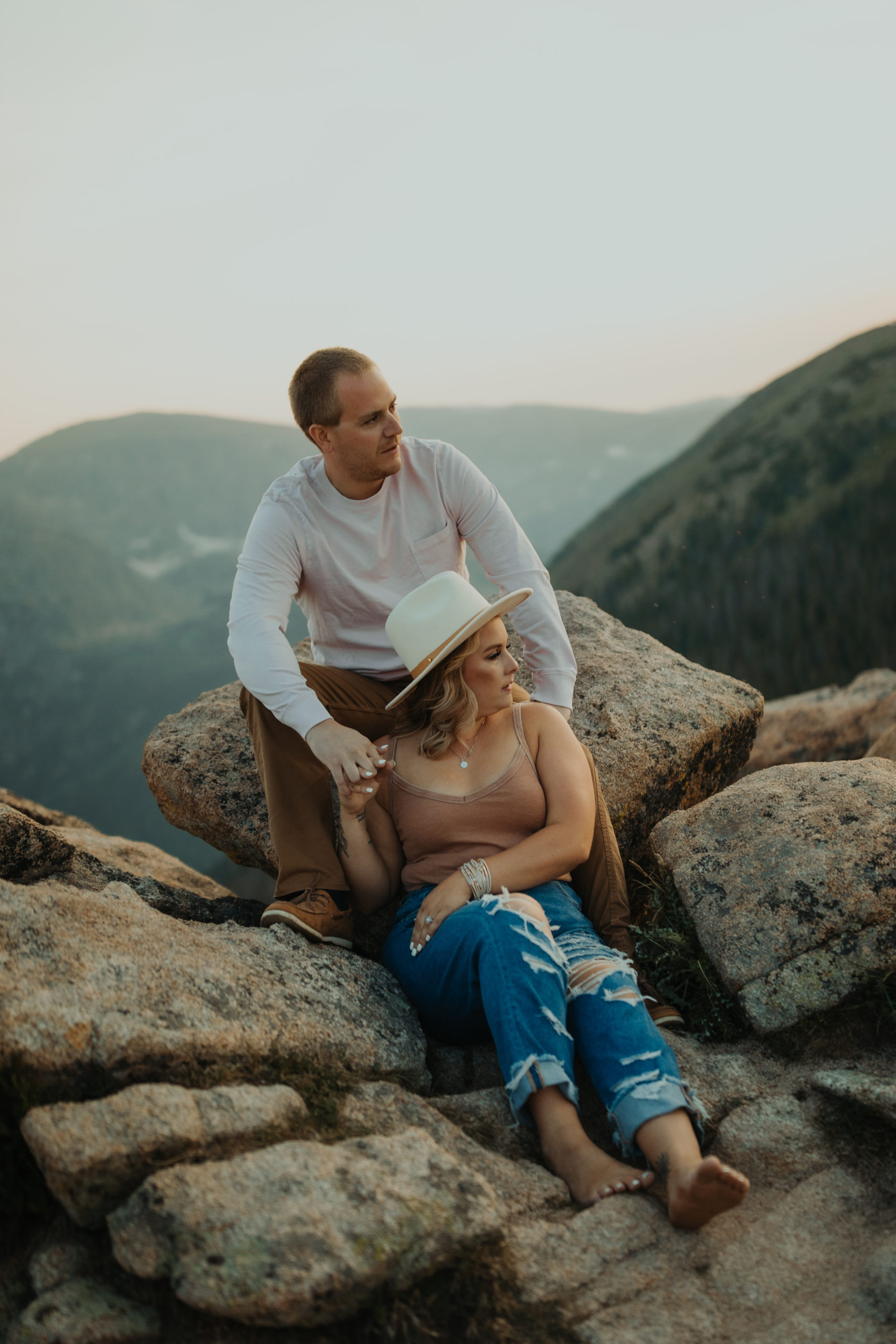 Close up of couple cuddle up on some rocks with an epic mountain background