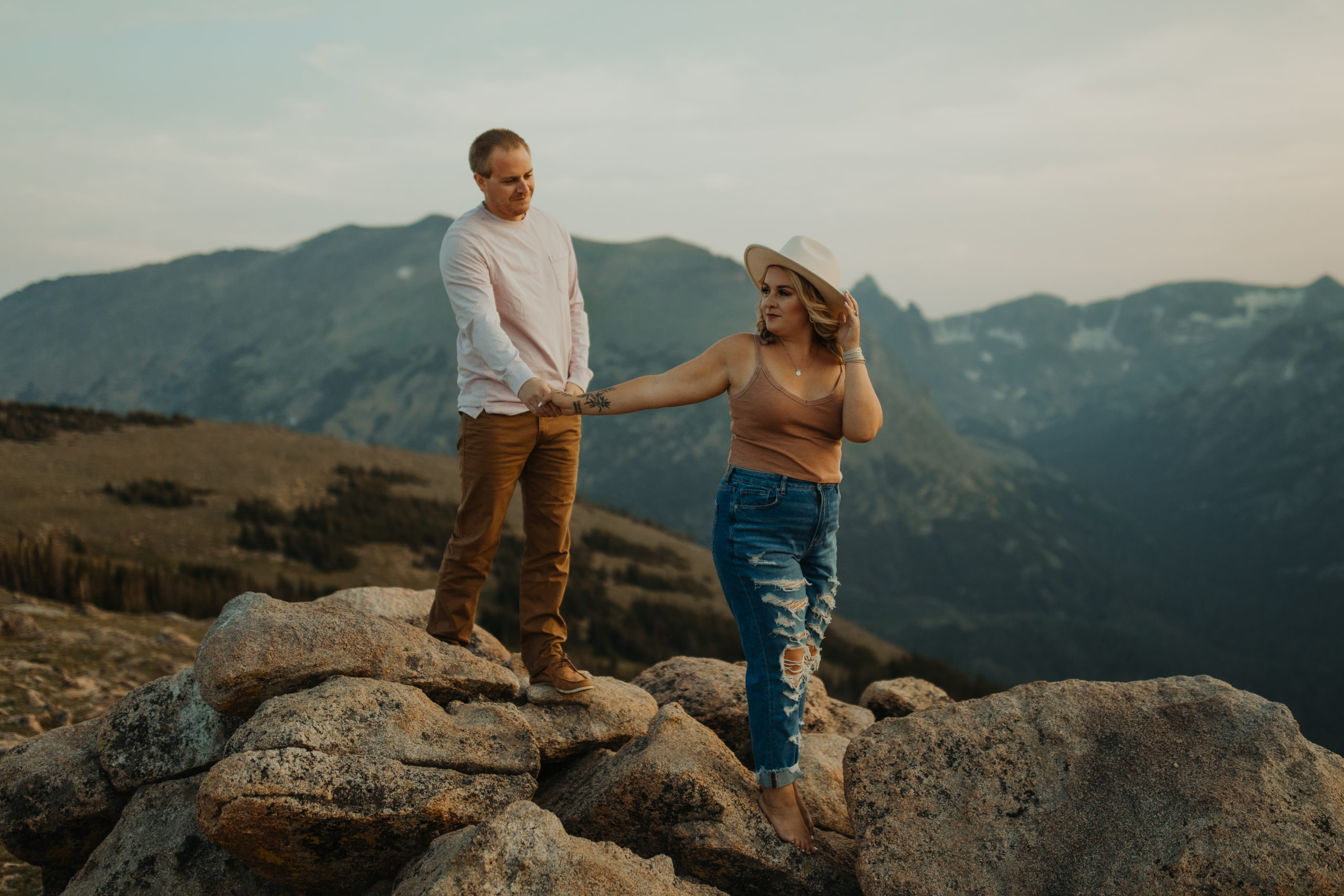 Couple standing on rocks holding hands with the Rocky Mountain National Park behind them