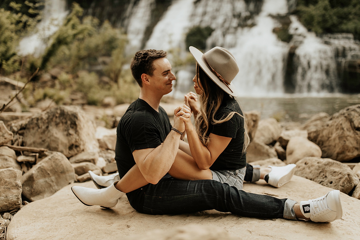 Couple sitting together holding hands by a waterfall