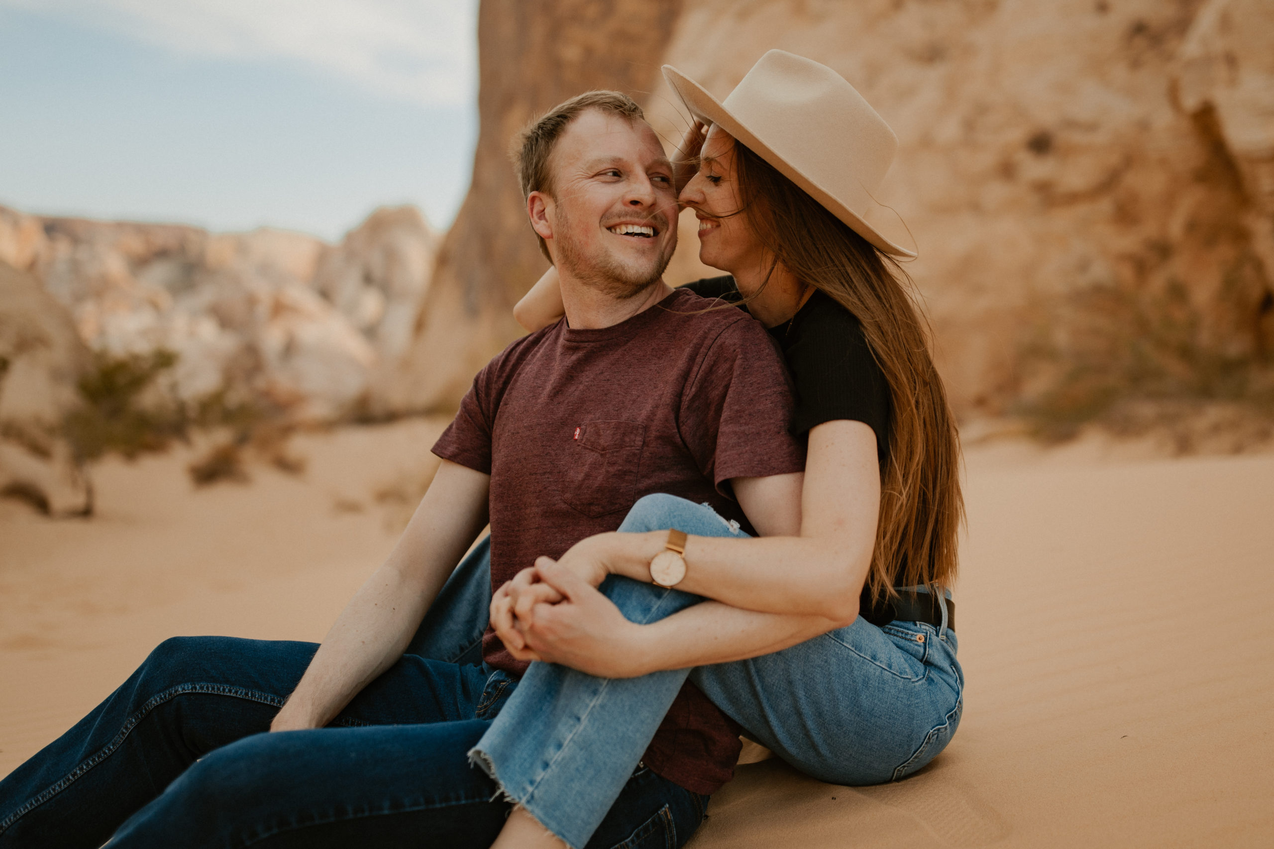 couple sitting together in the desert during their engagement session