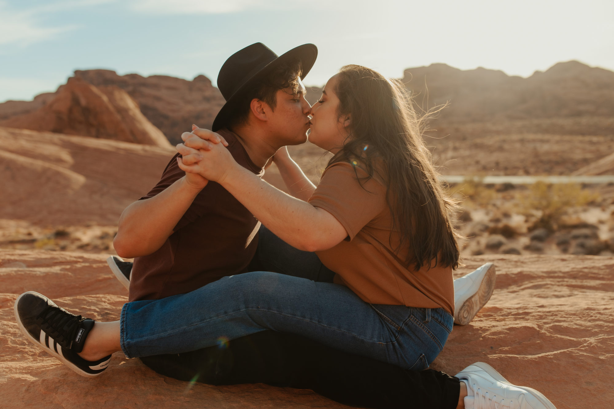 Girlfriend sitting on boyfriend's lap in valley of fire during couples photoshoot
