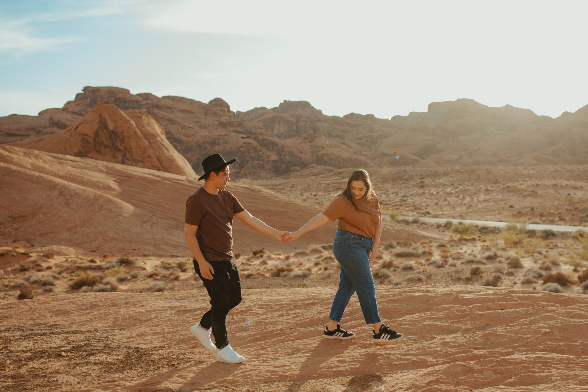 Girlfriend walking and leading boyfriend in the desert