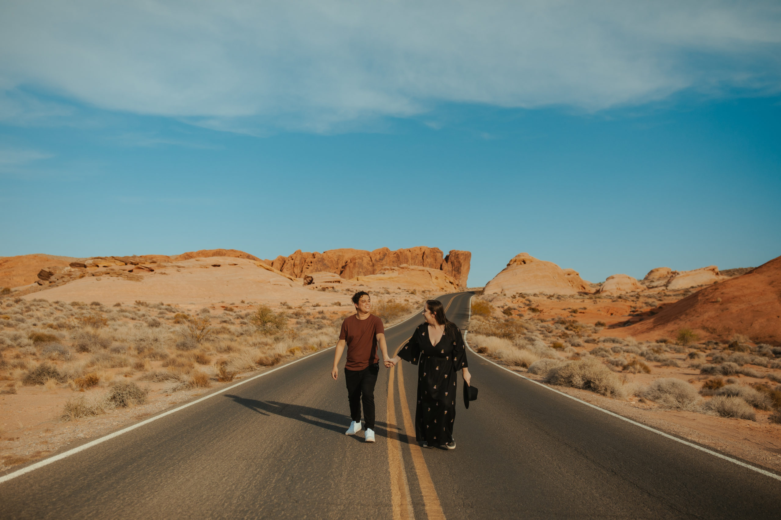 Boyfriend and girlfriend walking down a dirt road in the desert