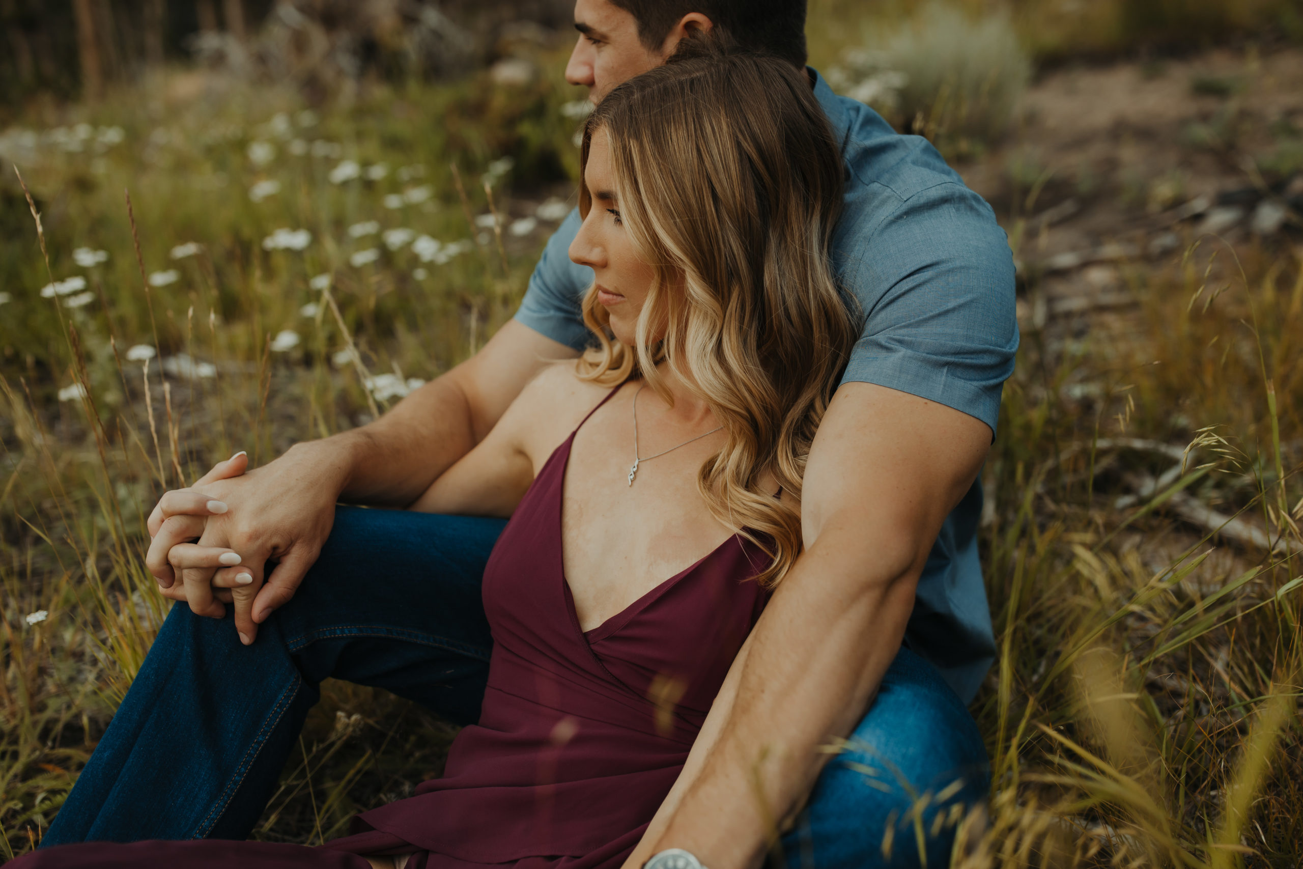 engaged couple sitting in a meadow