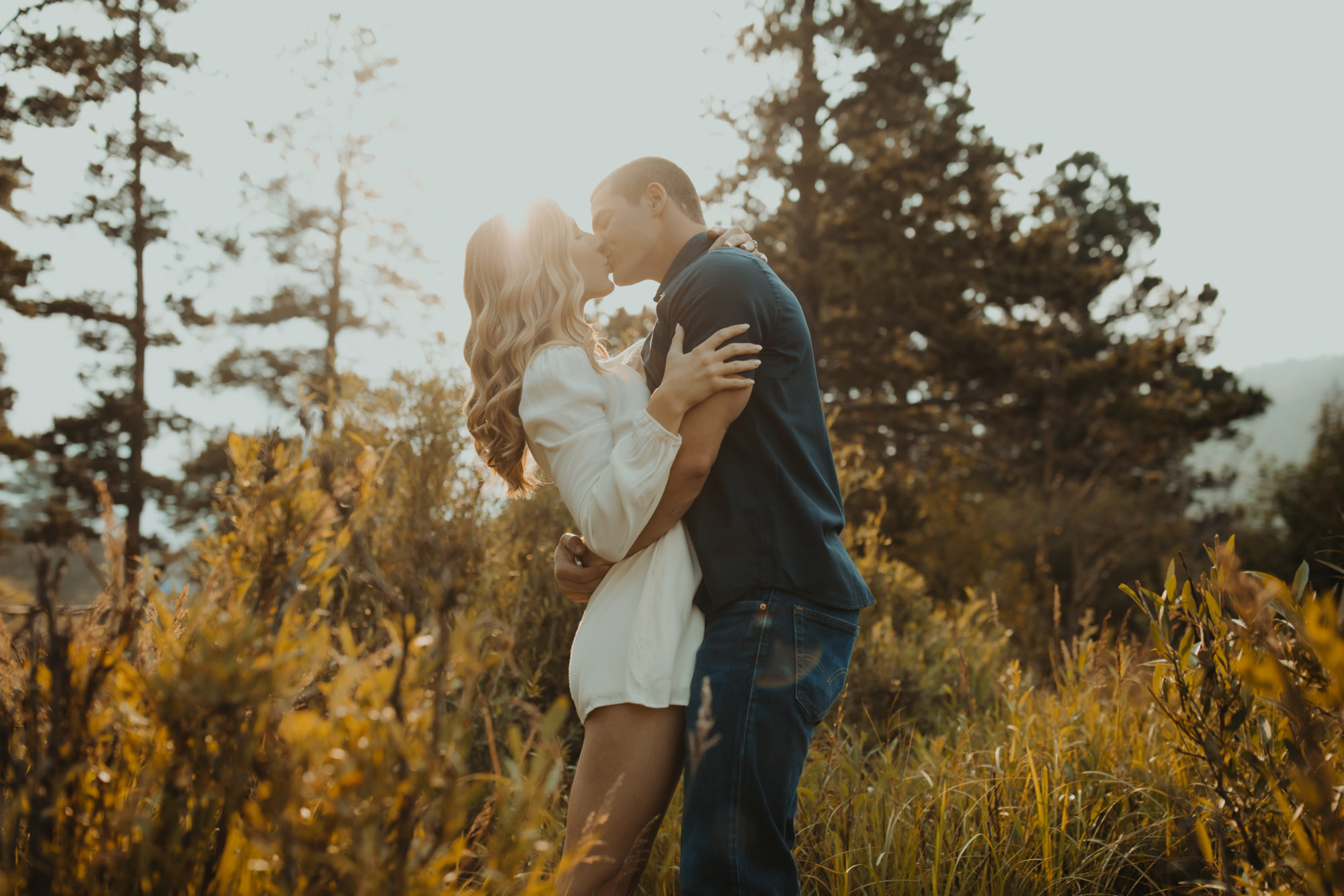 engaged couple kissing in a field in the PNW