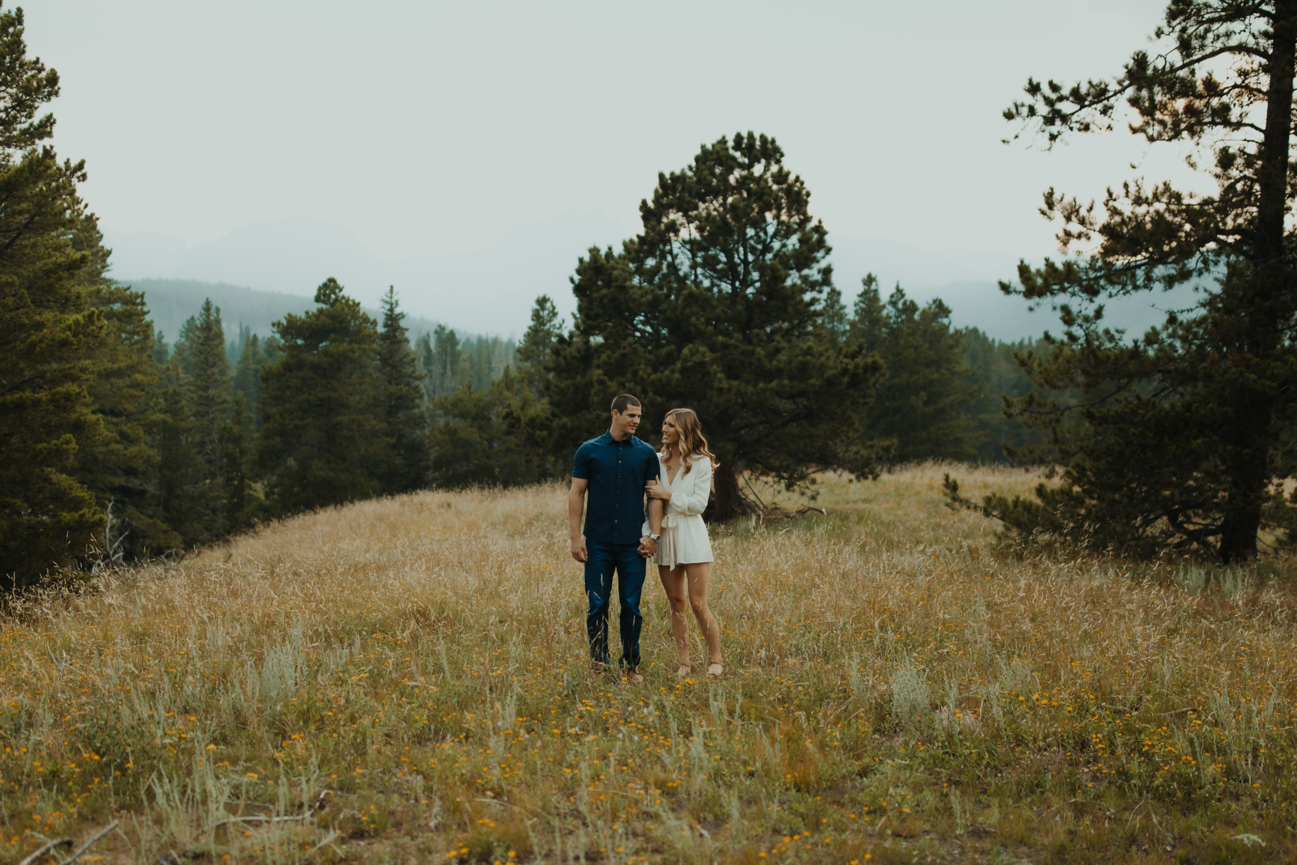 engaged couple walking through a field in the PNW