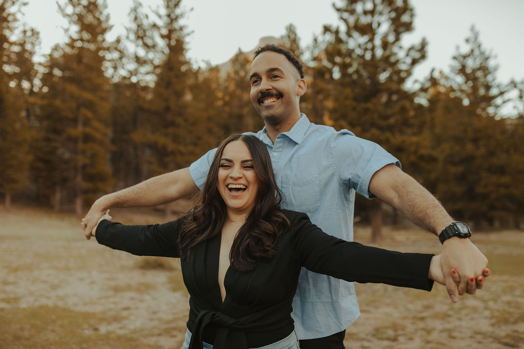 couple laughing while doing airplane arms during their engagement session at mt. Charleston