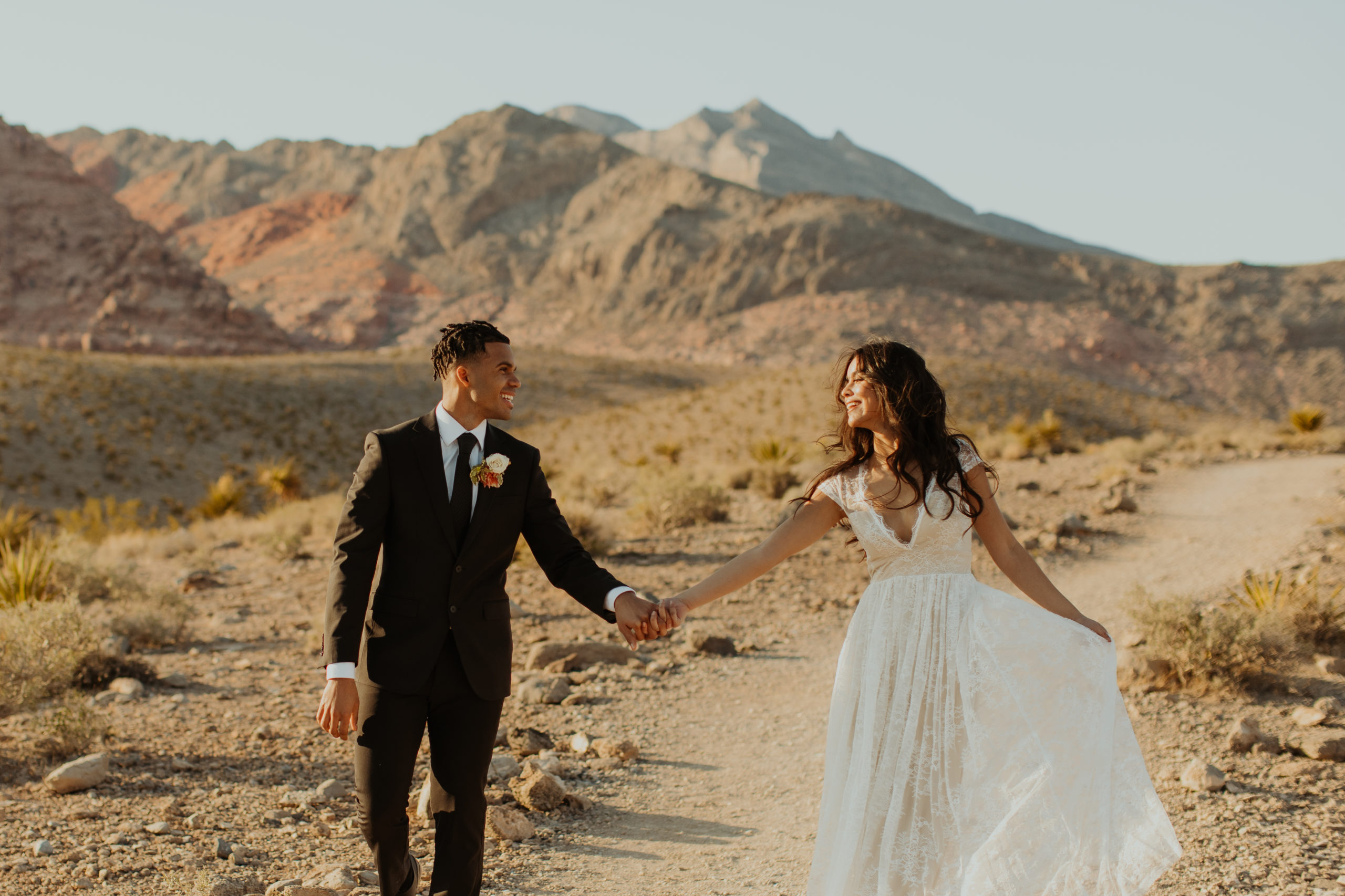 bride and groom walking through the desert holding hands