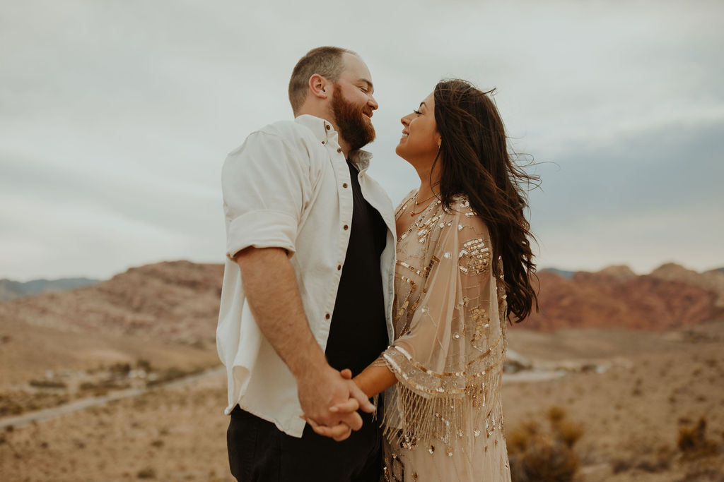 couple holding hands in the desert looking at eachother and smiling during their vow renewal