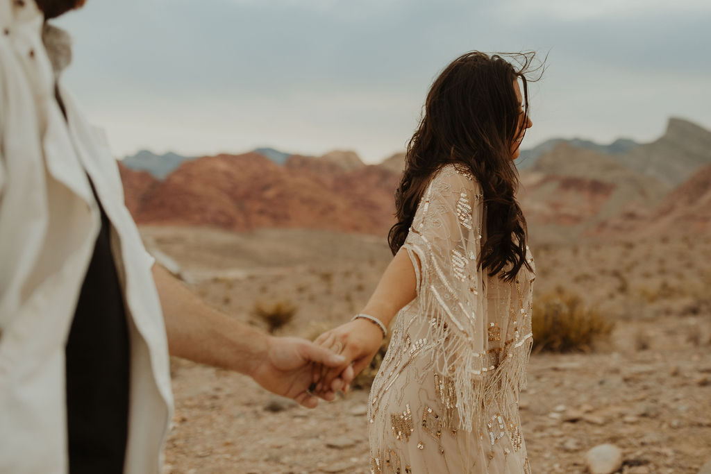couple walking through the desert holding hands in Las Vegas during their vow renewal photoshoot