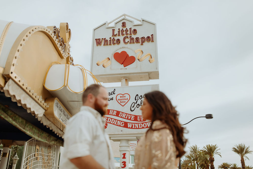 Couple standing in front of the little white chapel sign in Las Vegas