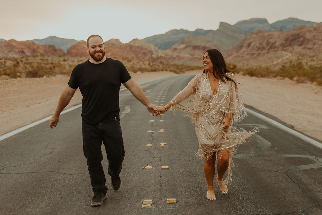 couple running down the road in red rock canyon desert in las vegas during their vow renewal