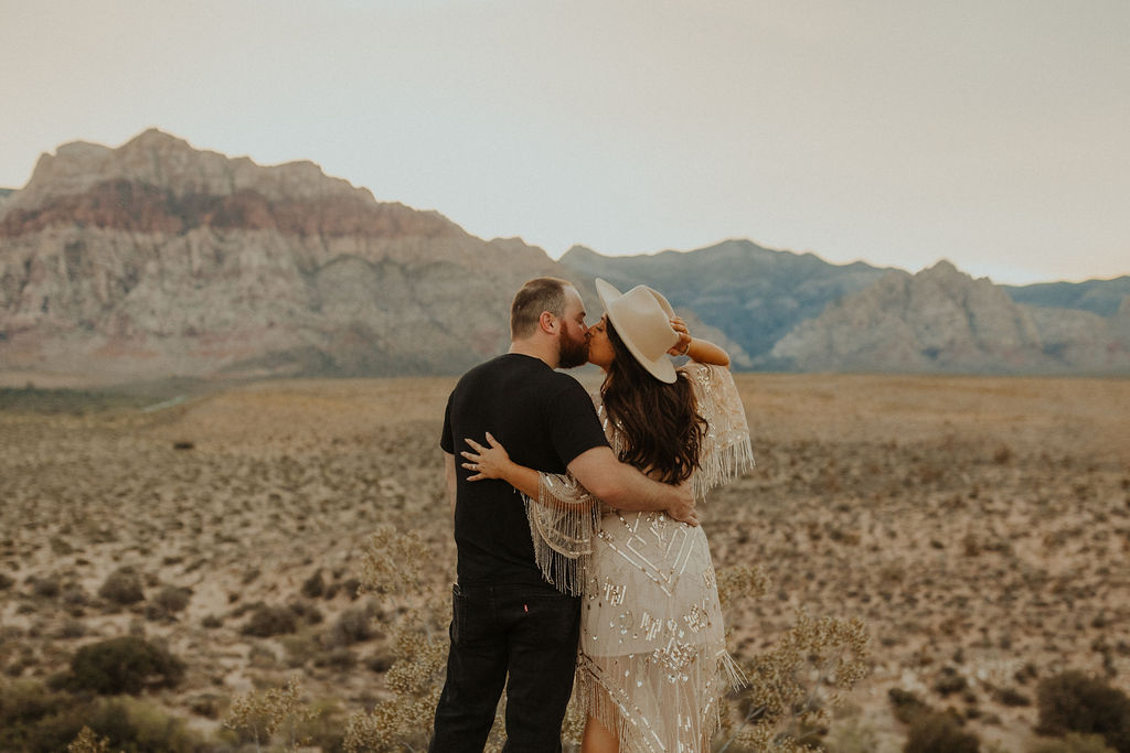 couple facing away from the camera kissing with red rock canyon las vegas in the background