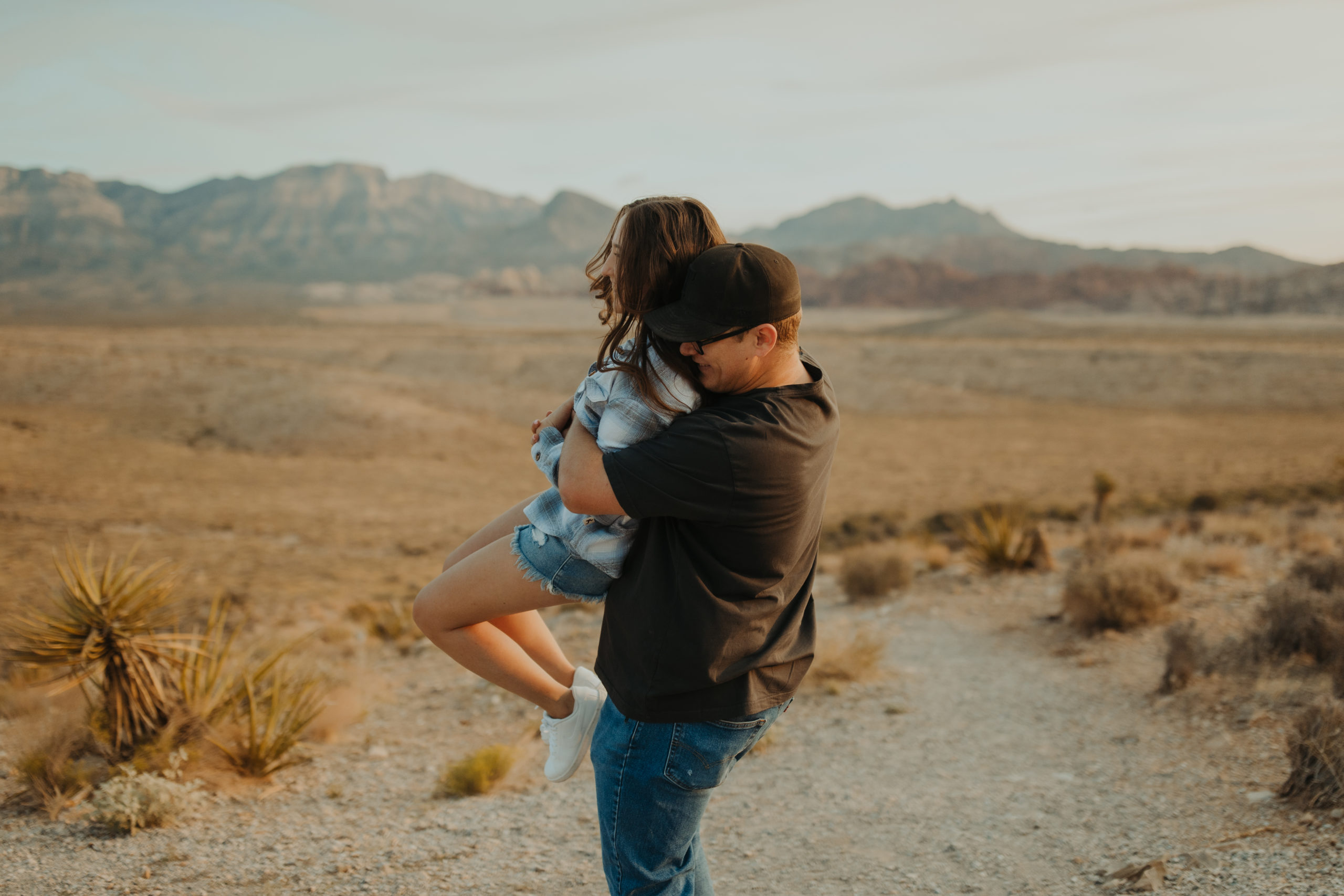 boyfriend lifting and spinning his girlfriend around in the desert