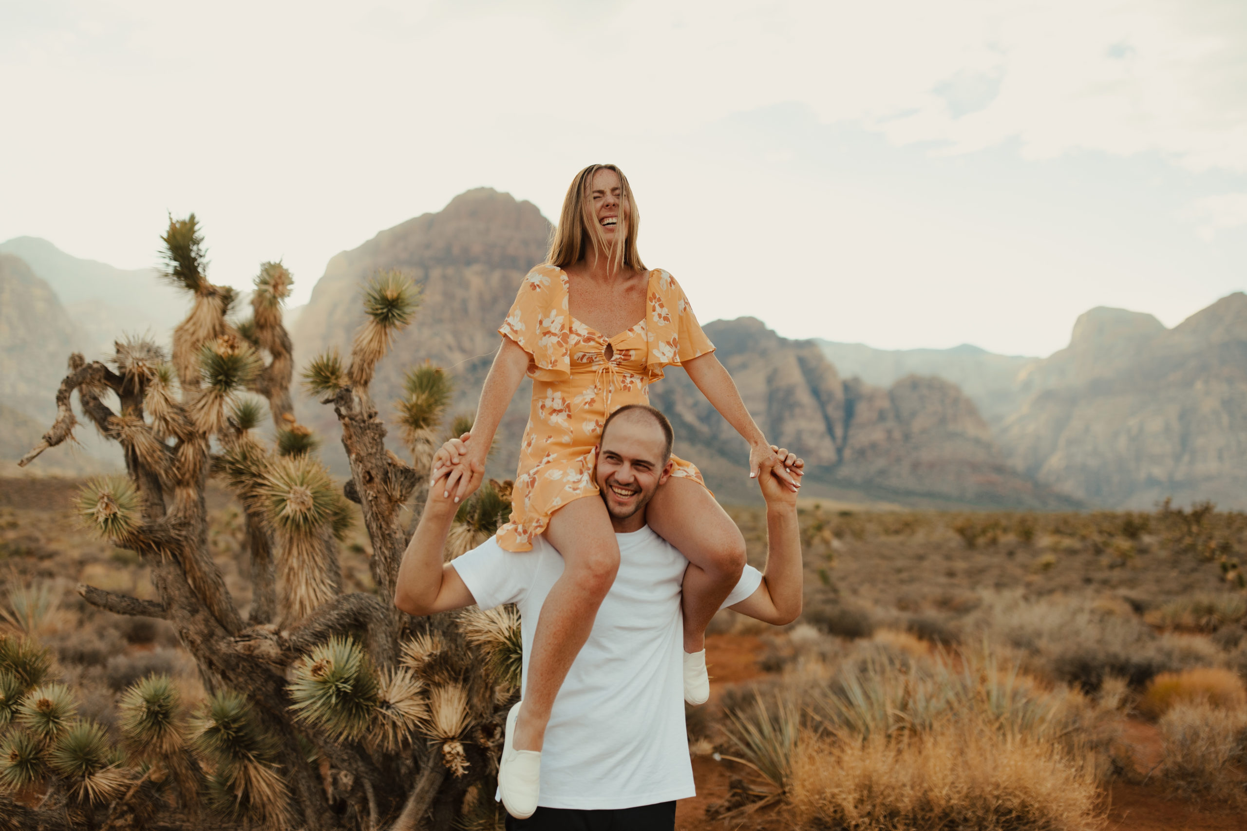 engaged couple with girlfriend on fiances shoulders in the desert