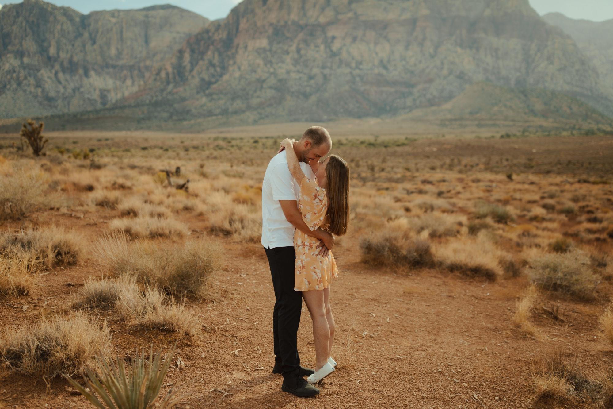 couple standing in the desert with the foreheads touching during their engagement session