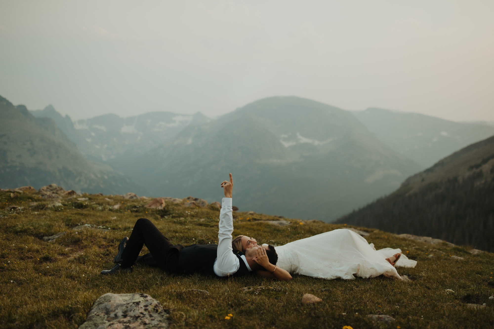 Bride and Groom laying down in the mountains at Rocky Mountain National Park Looking up at the sky