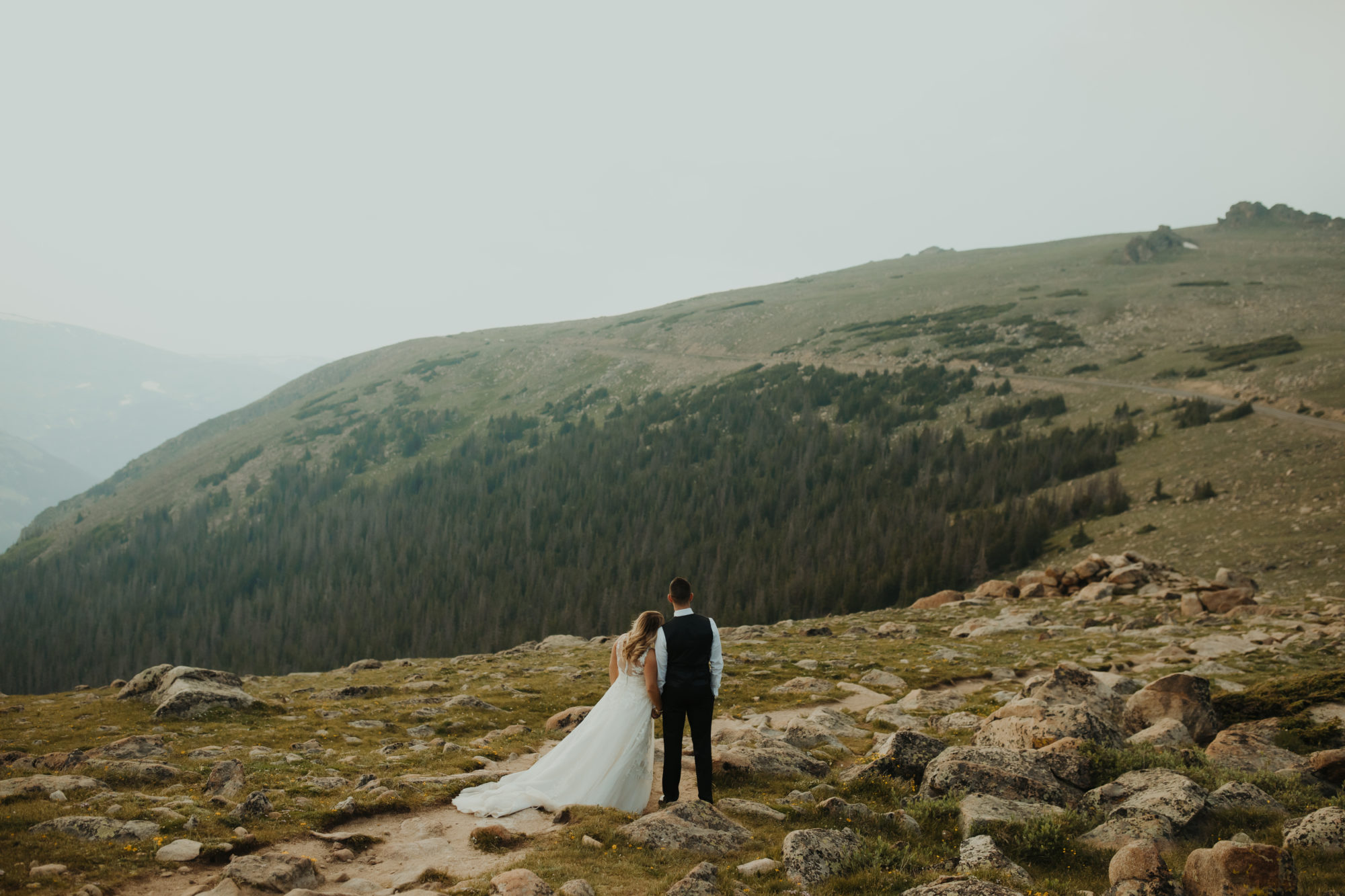 bride and groom walking on a mountain in rocky mountain national park while holding hands