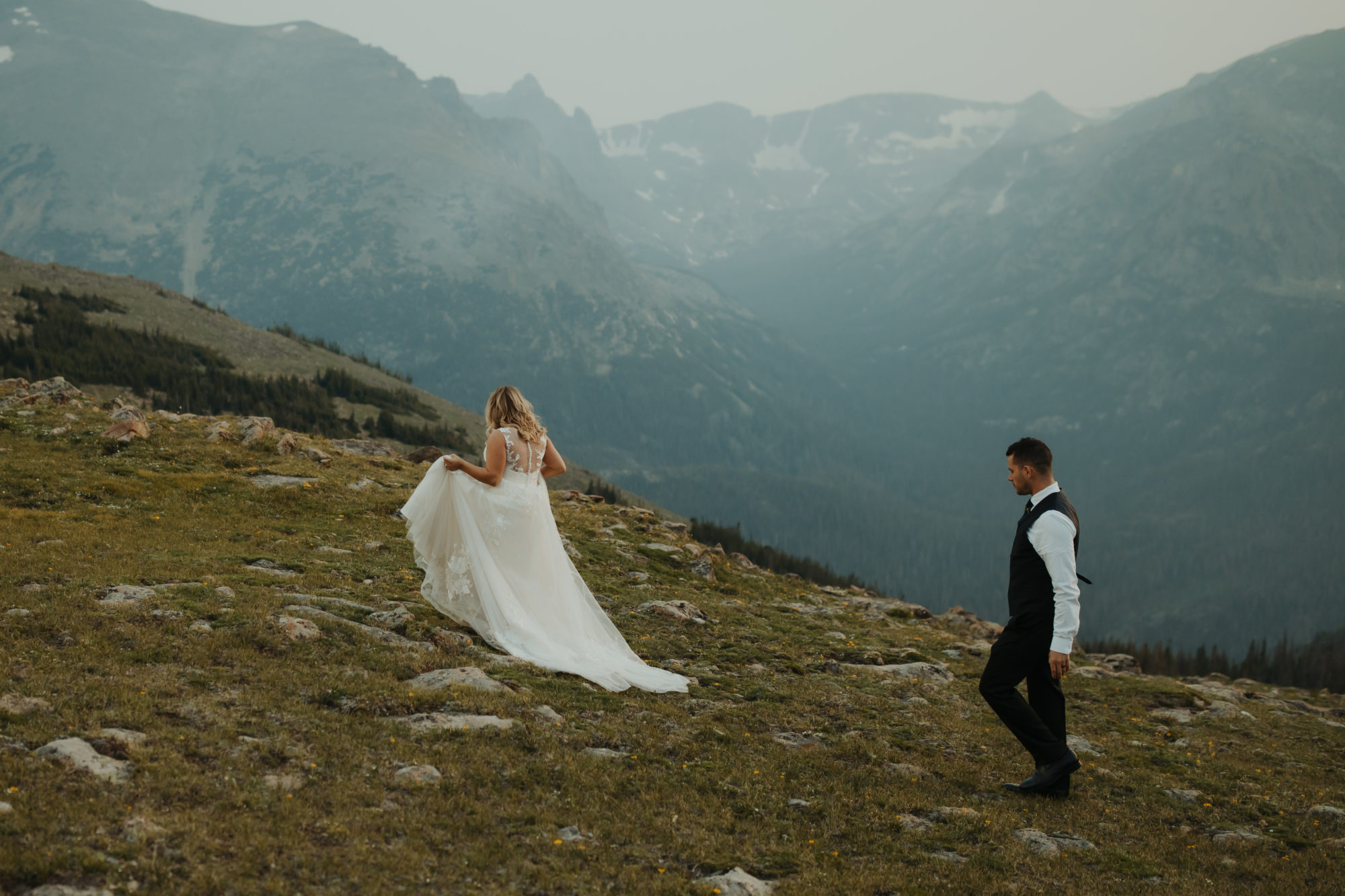 Bride leading groom up a hill in rocky mountain national park 