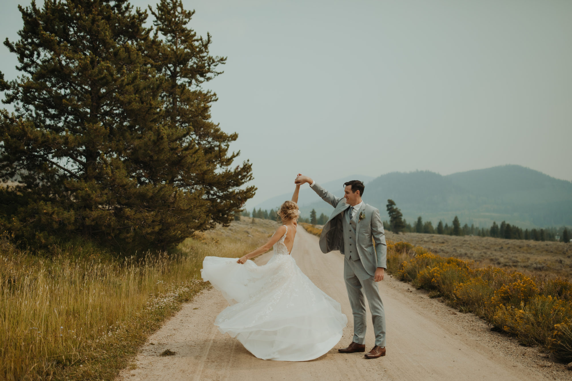 groom twirling bride around in a field