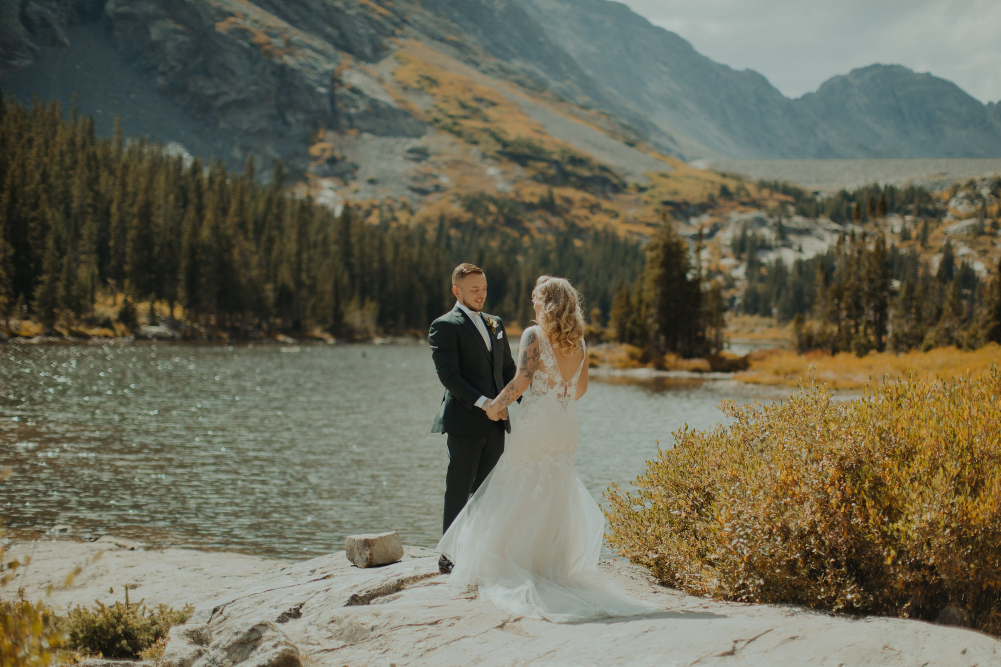 bride and groom holding hands on the bank of lake in breckenridge colorado