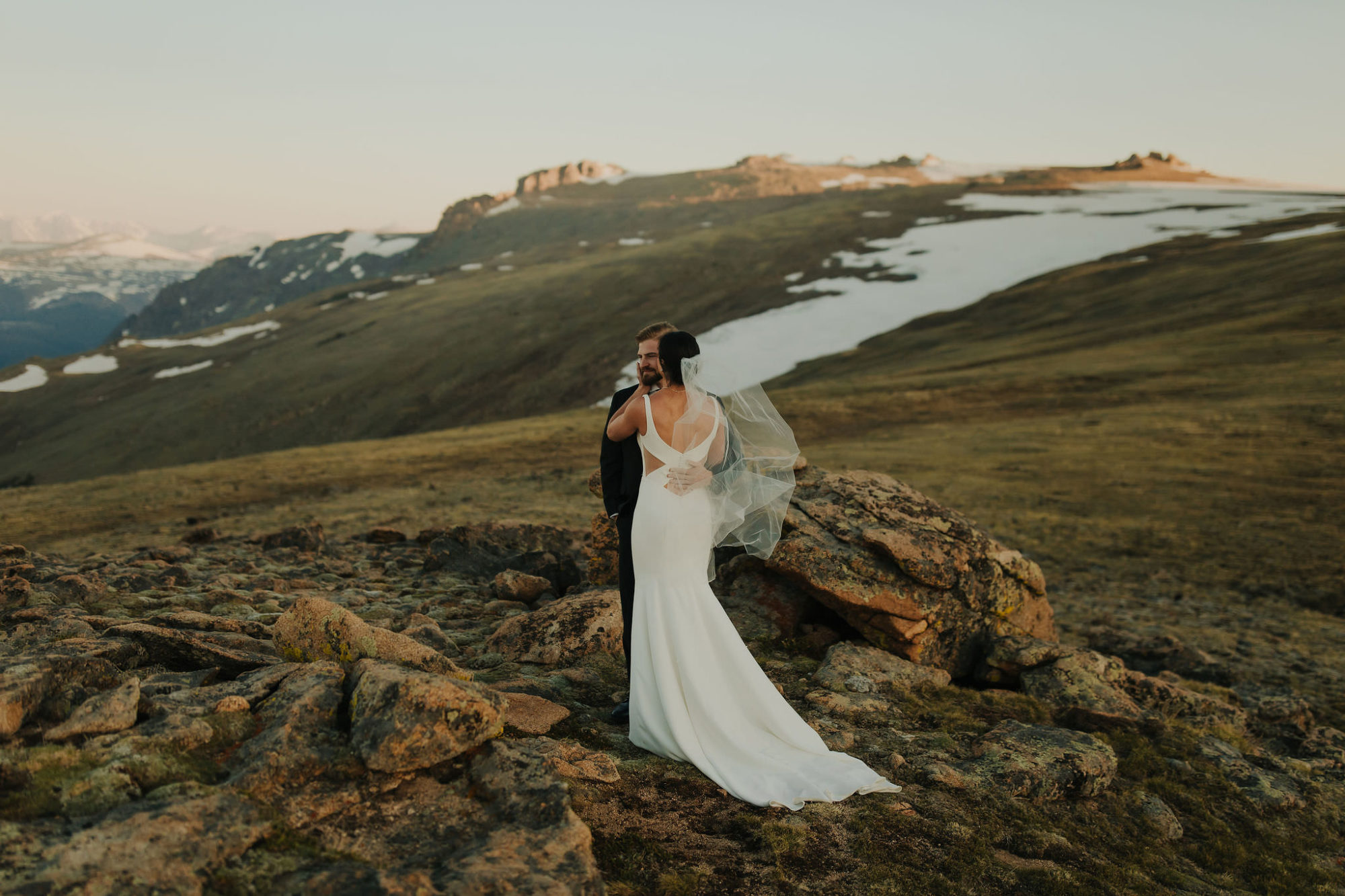 bride and groom standing on a rock face in rocky mountain national park
