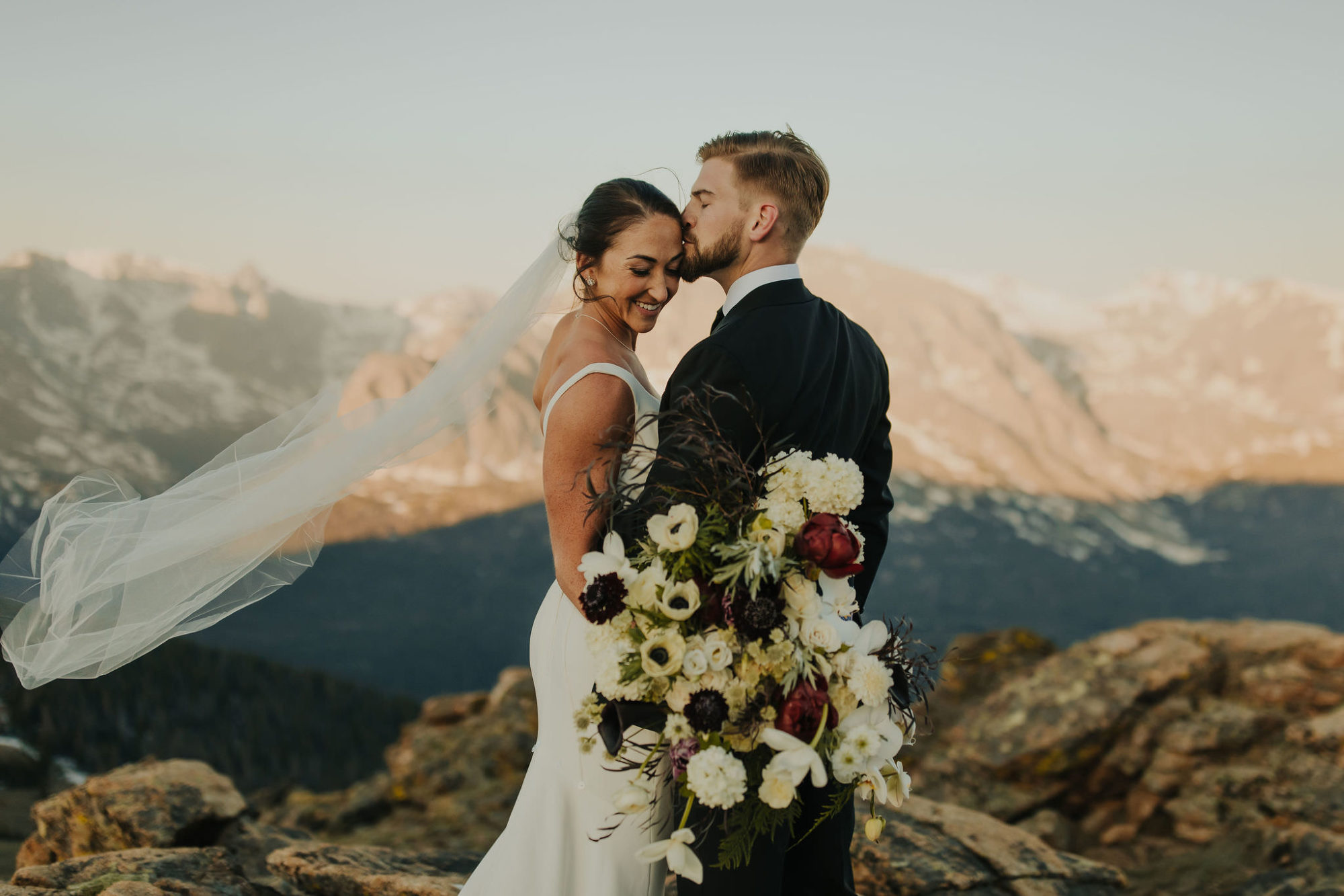 groom kissing his bride on the temple during their elopement ceremony in rocky mountain national park
