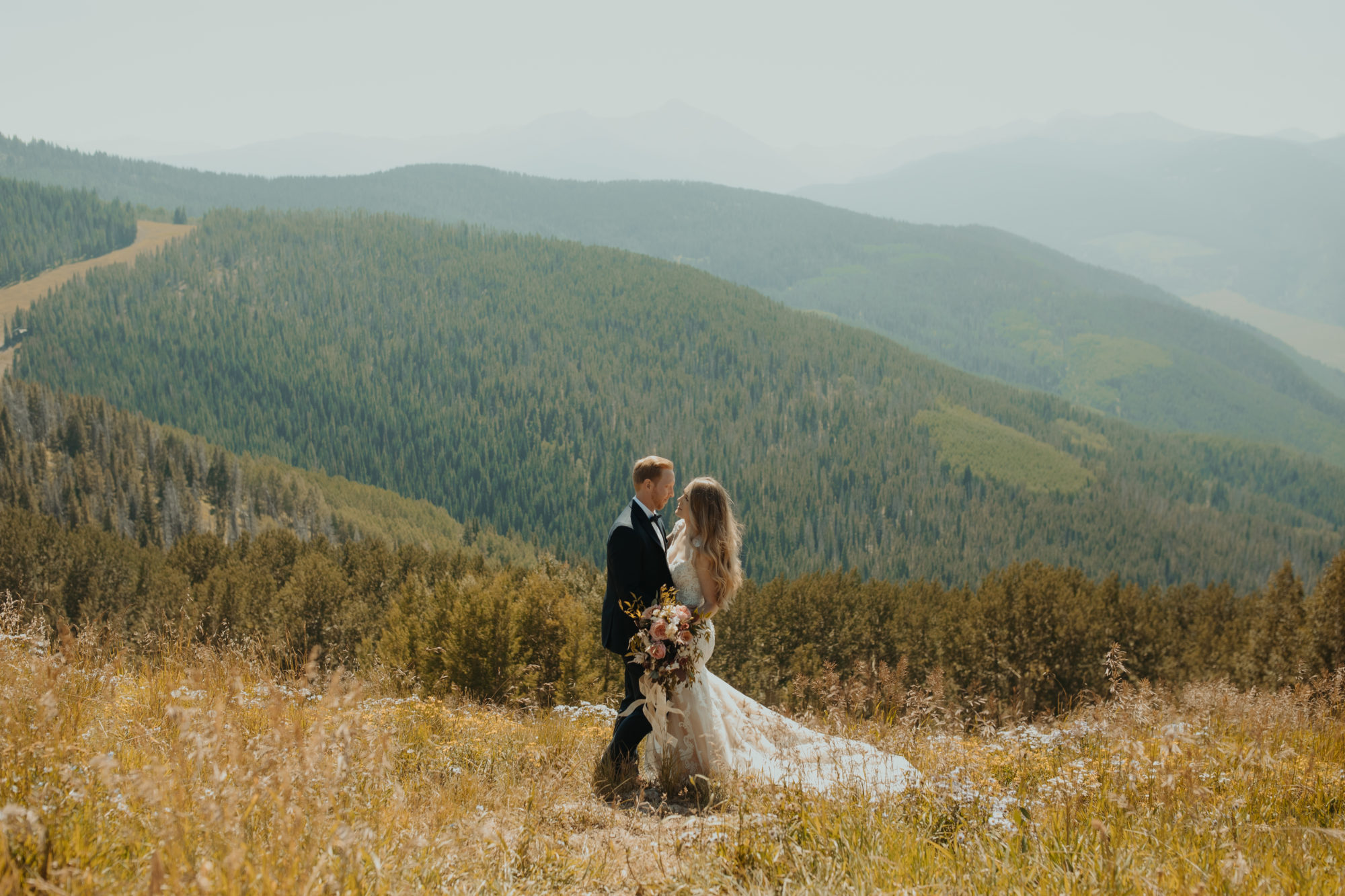 bride and groom standing in a field ontop of a mountain in vail colorado
