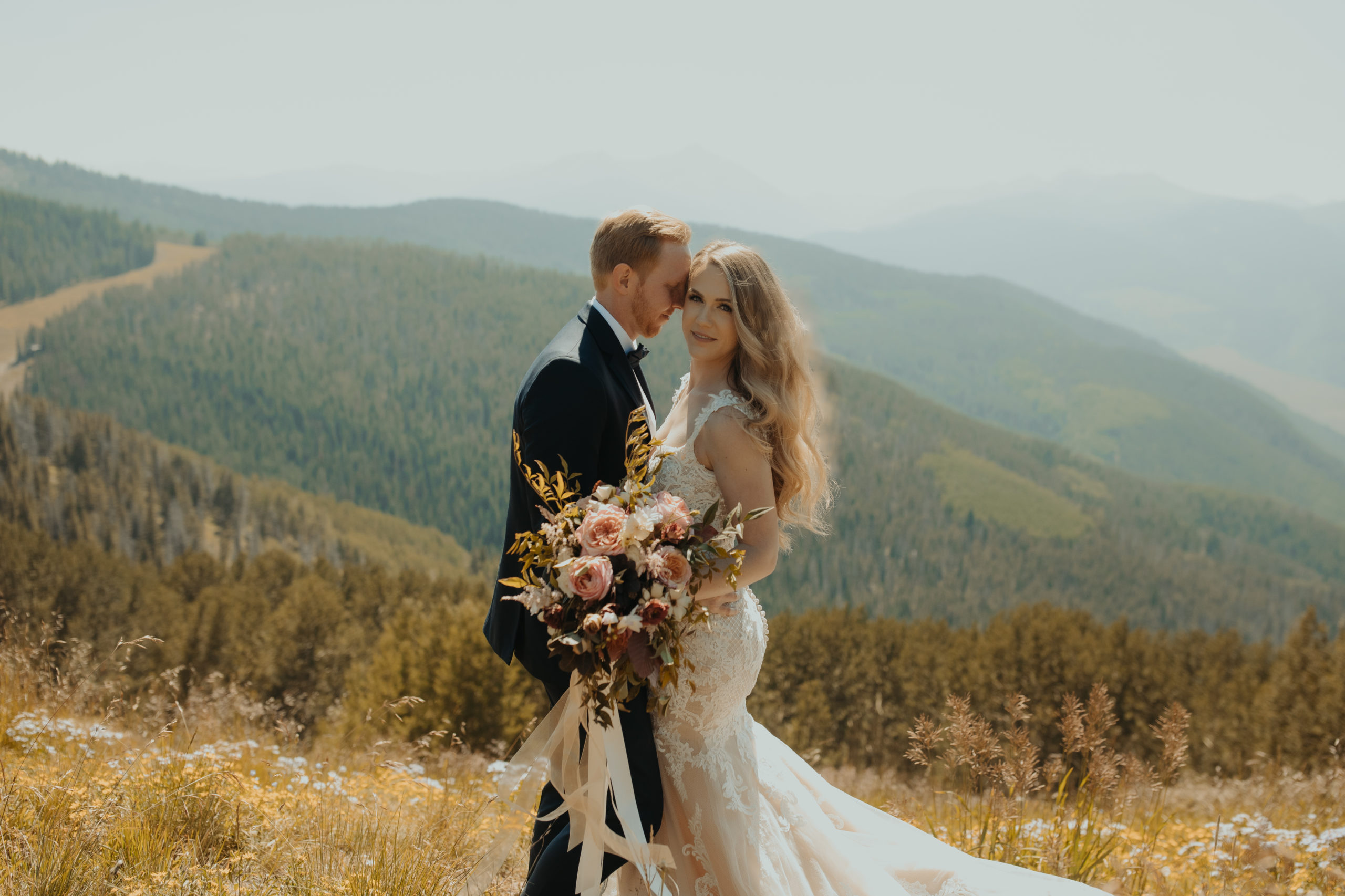 bride and groom standing on a mountain in veils colorado 