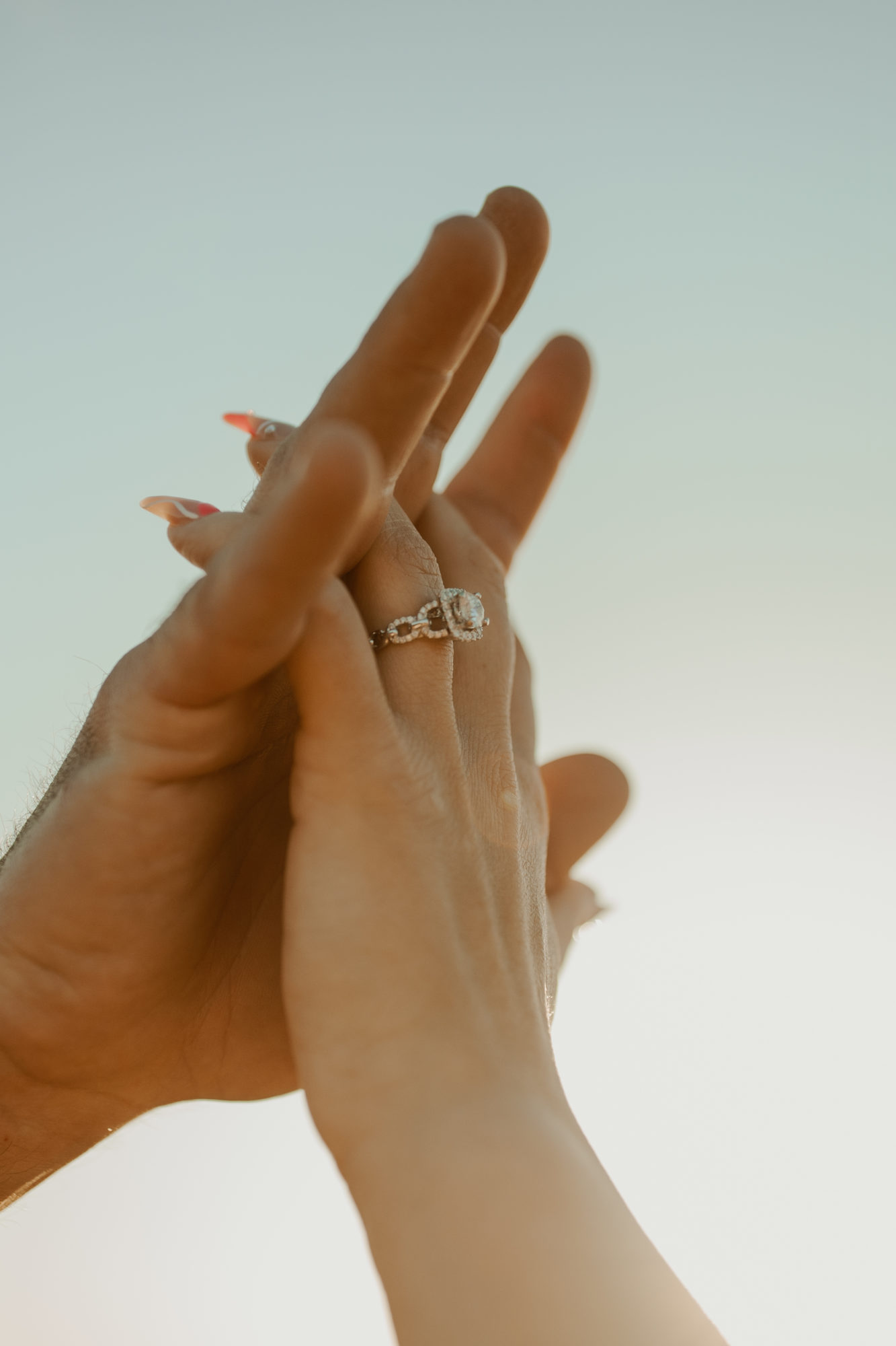 photo of newly engaged couples hands laced together and showing off her engagement ring