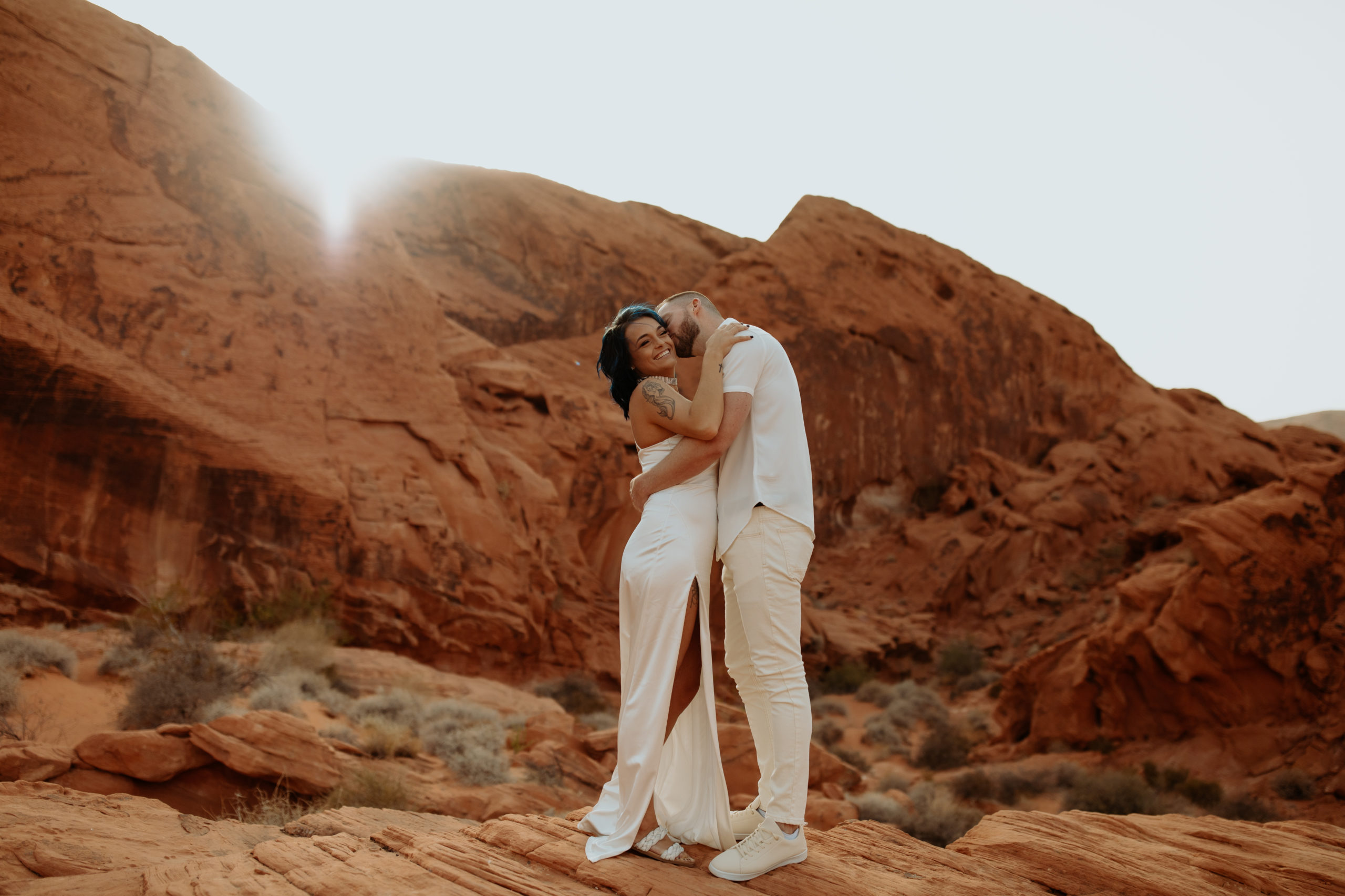 fiance kissing his finacee on the cheek during their engagement photos in valley of fire during a dust storm