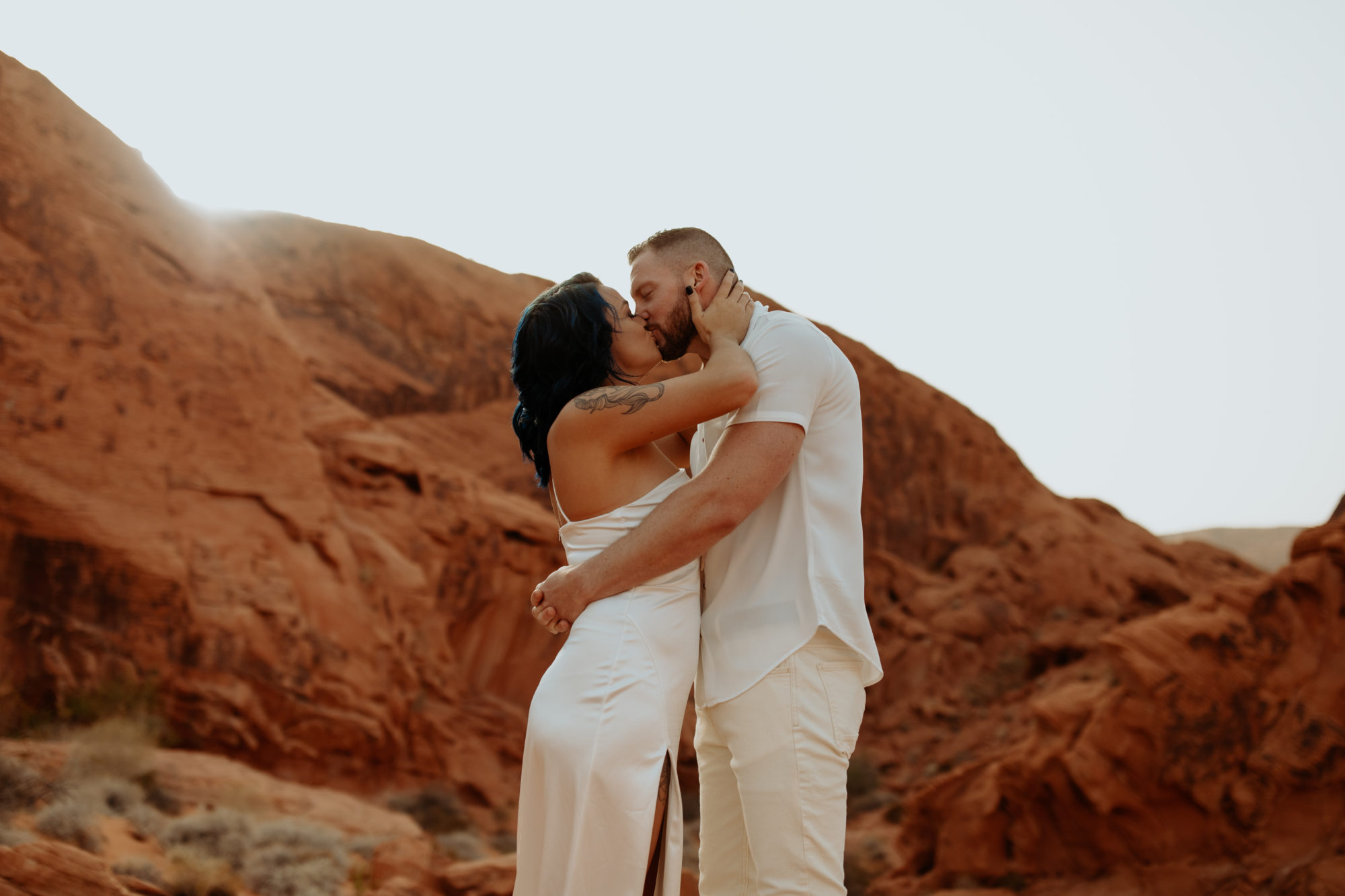 fiancee grabbing her fiances face and kissing him in valley of fire during a dust storm
