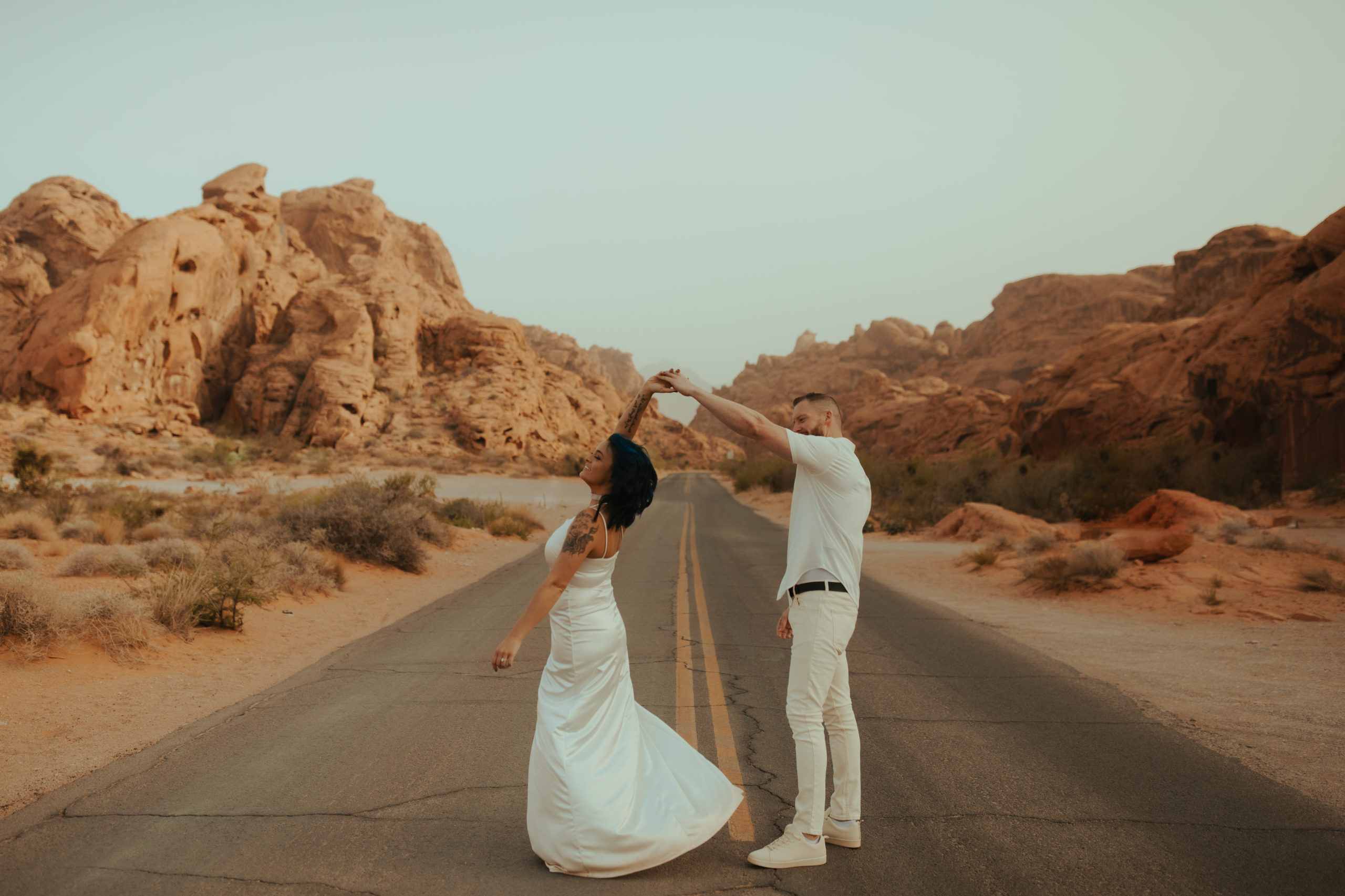 engaged couple dancing in the road in valley of fire during a dust storm