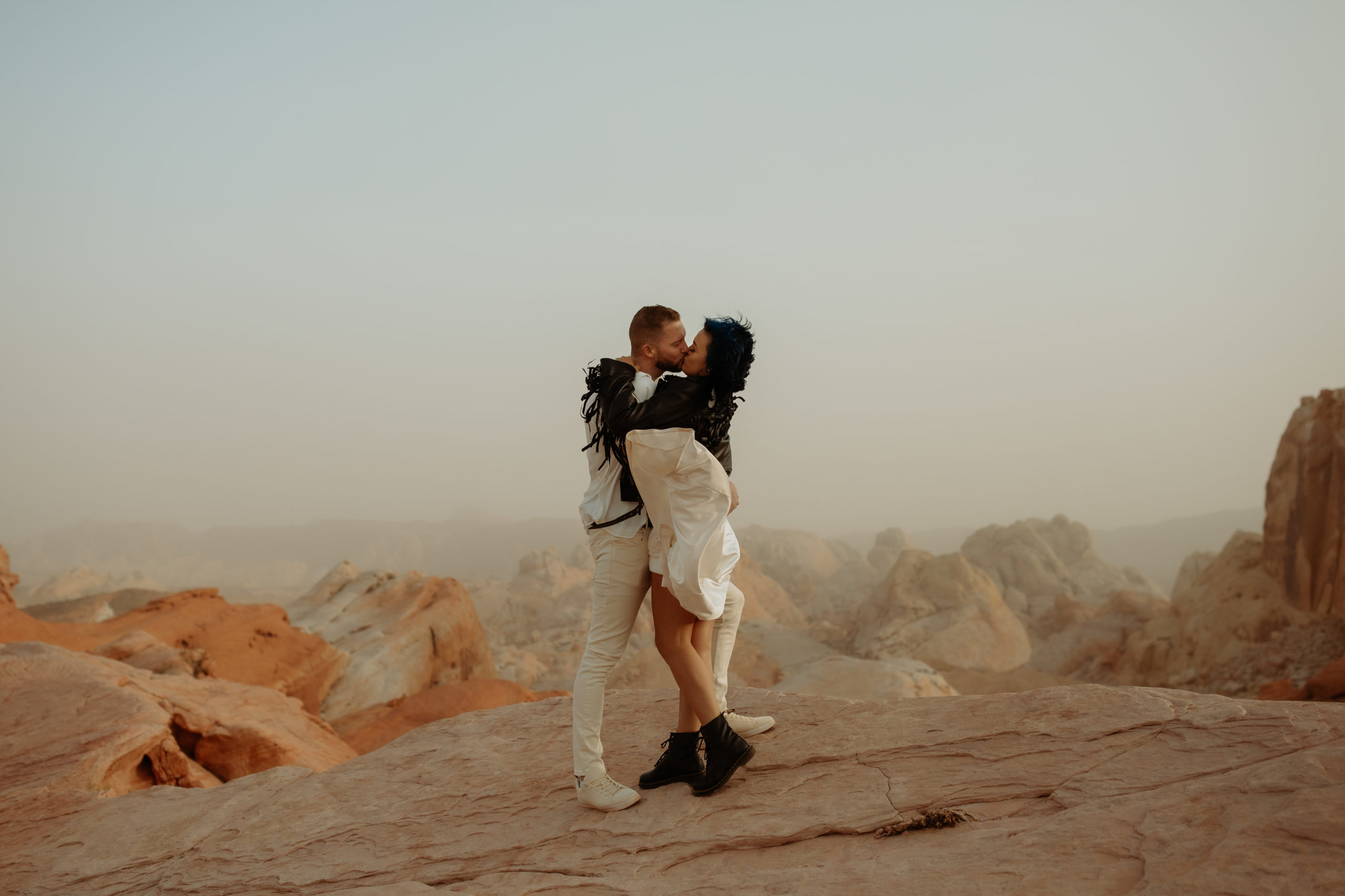 engaged couple kissing and hugging in a dust storm in valley of fire