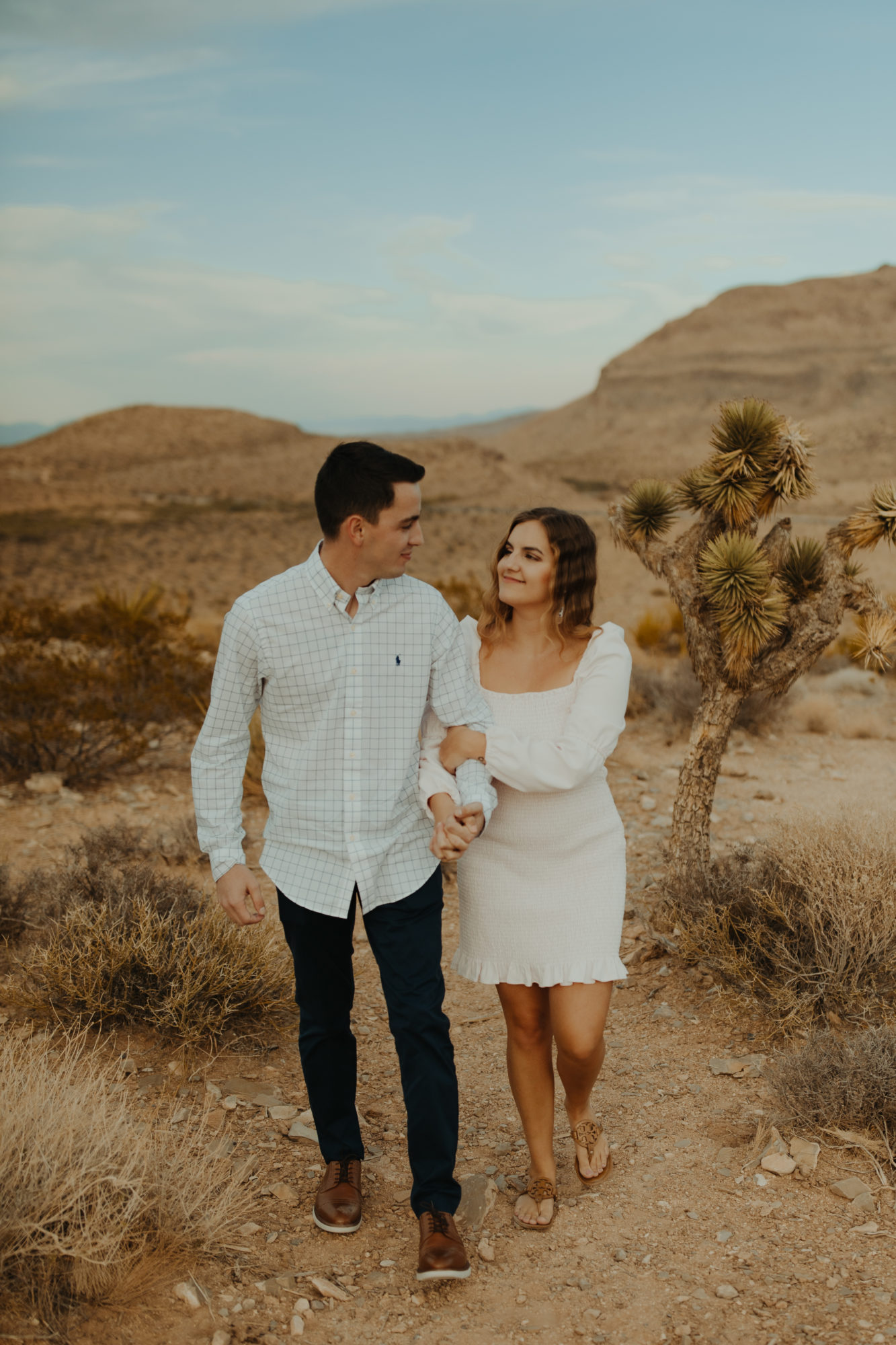 newly engaged couple walking through the desert together after he proposed