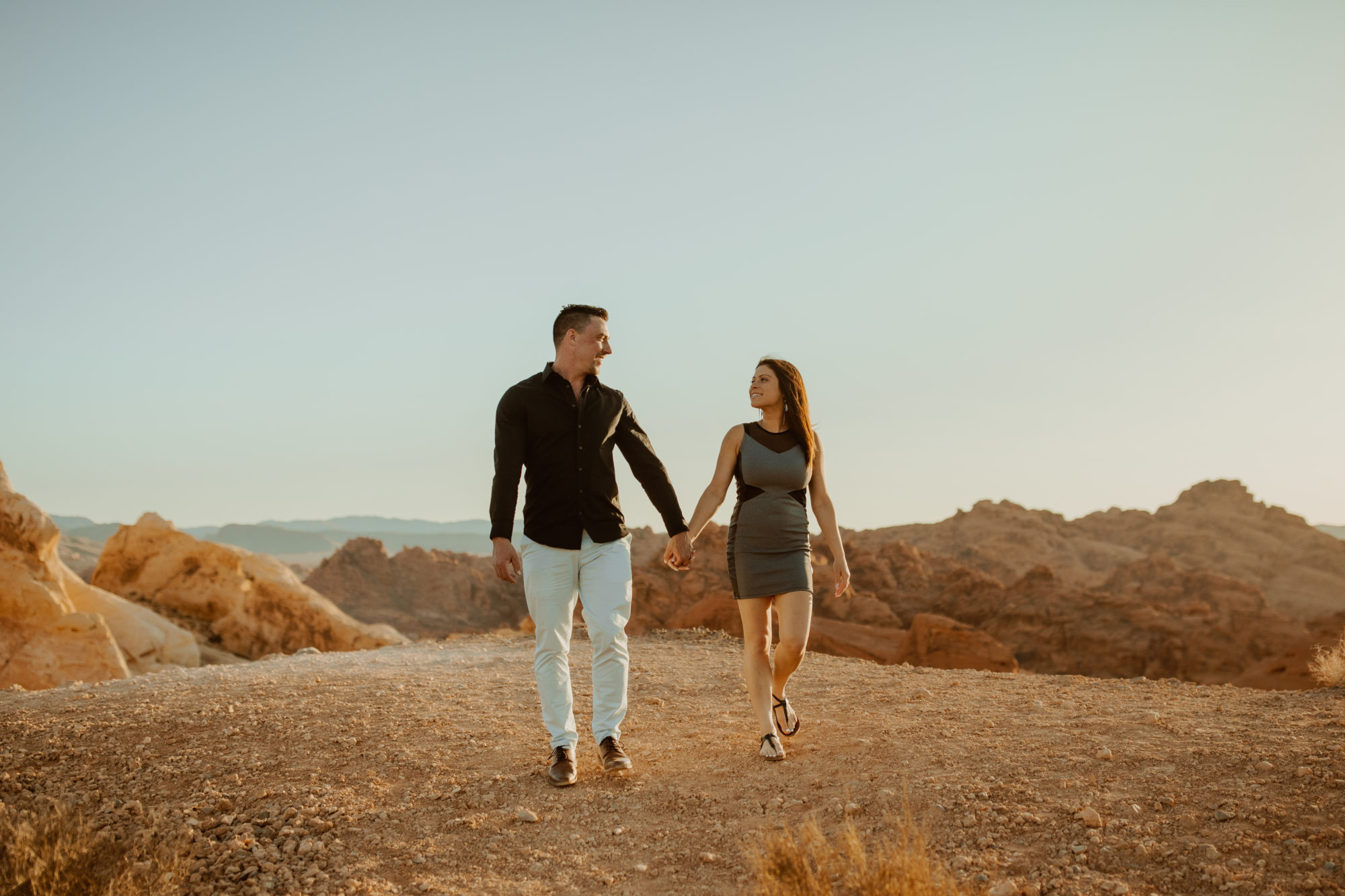 newly engaged couple holding hands and walking through the desert together