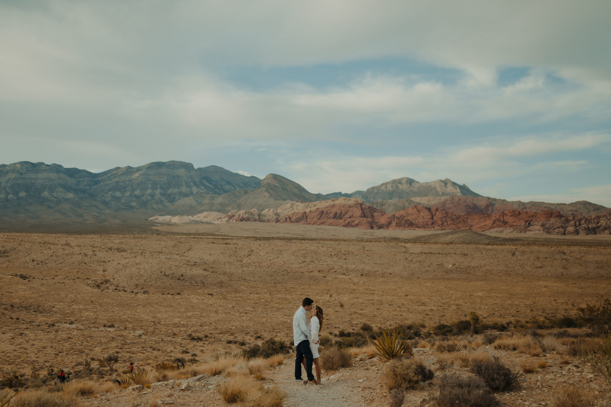 newly engaged couple embracing while kissing each other in the desert after just being proposed too