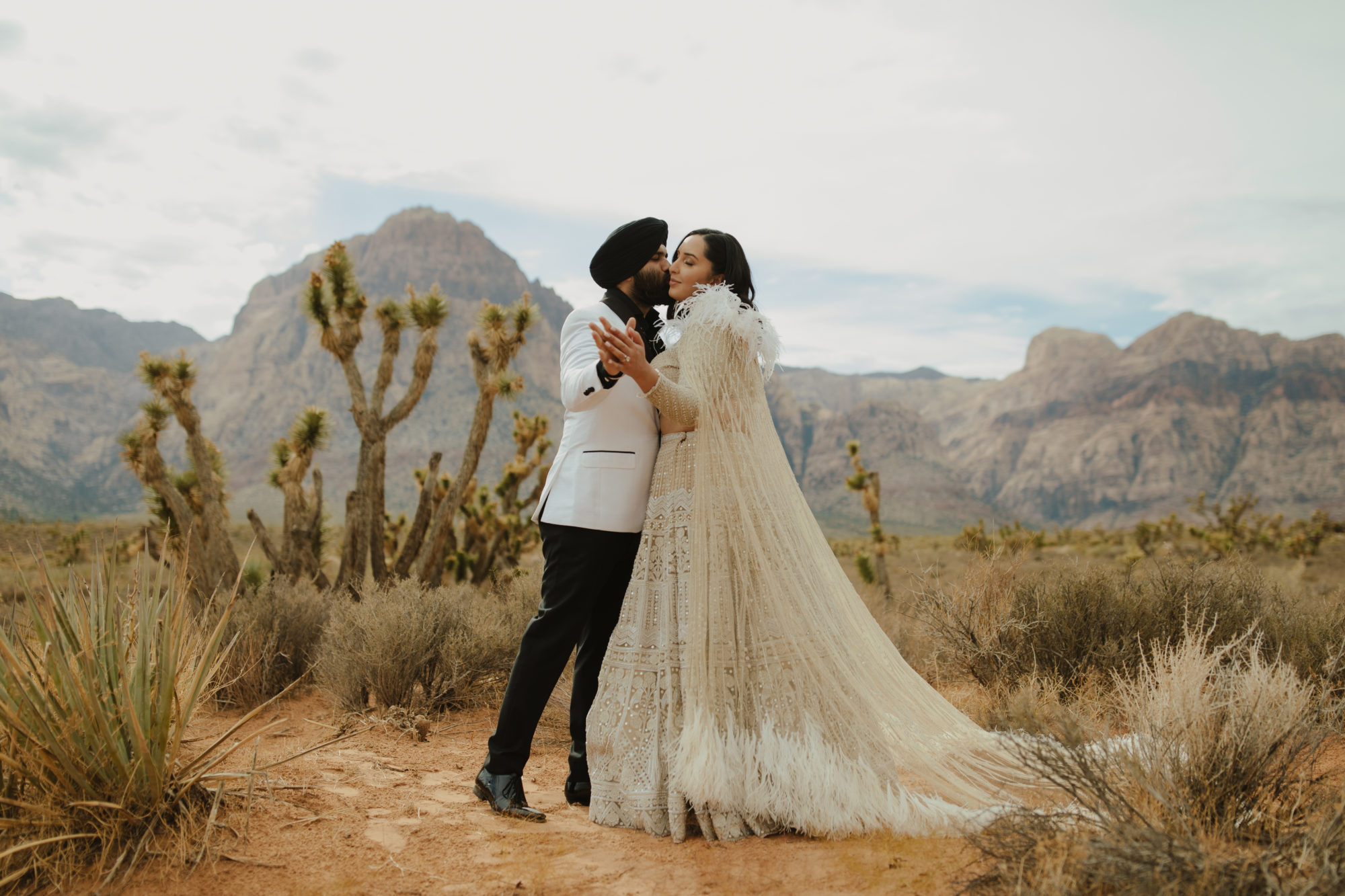 bride and groom in red rock canyon nevada with the groom kissing the brides cheek