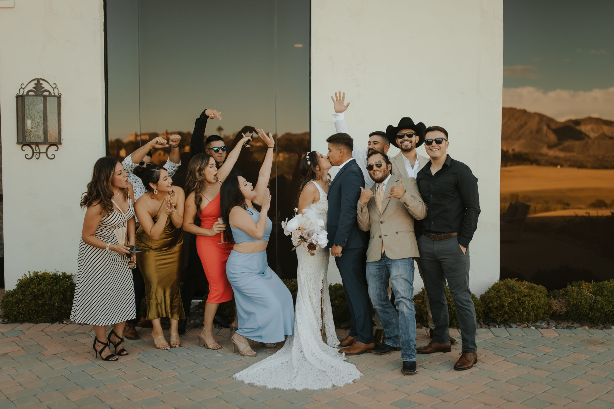 bride and groom kissing while their friends cheer in excitement