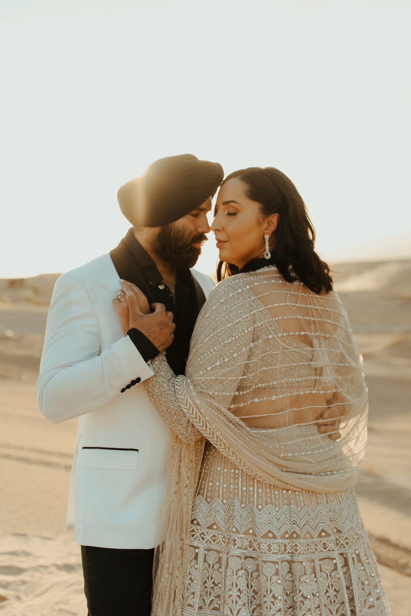 bride and groom putting their faces close together while enjoying the sunset in the desert